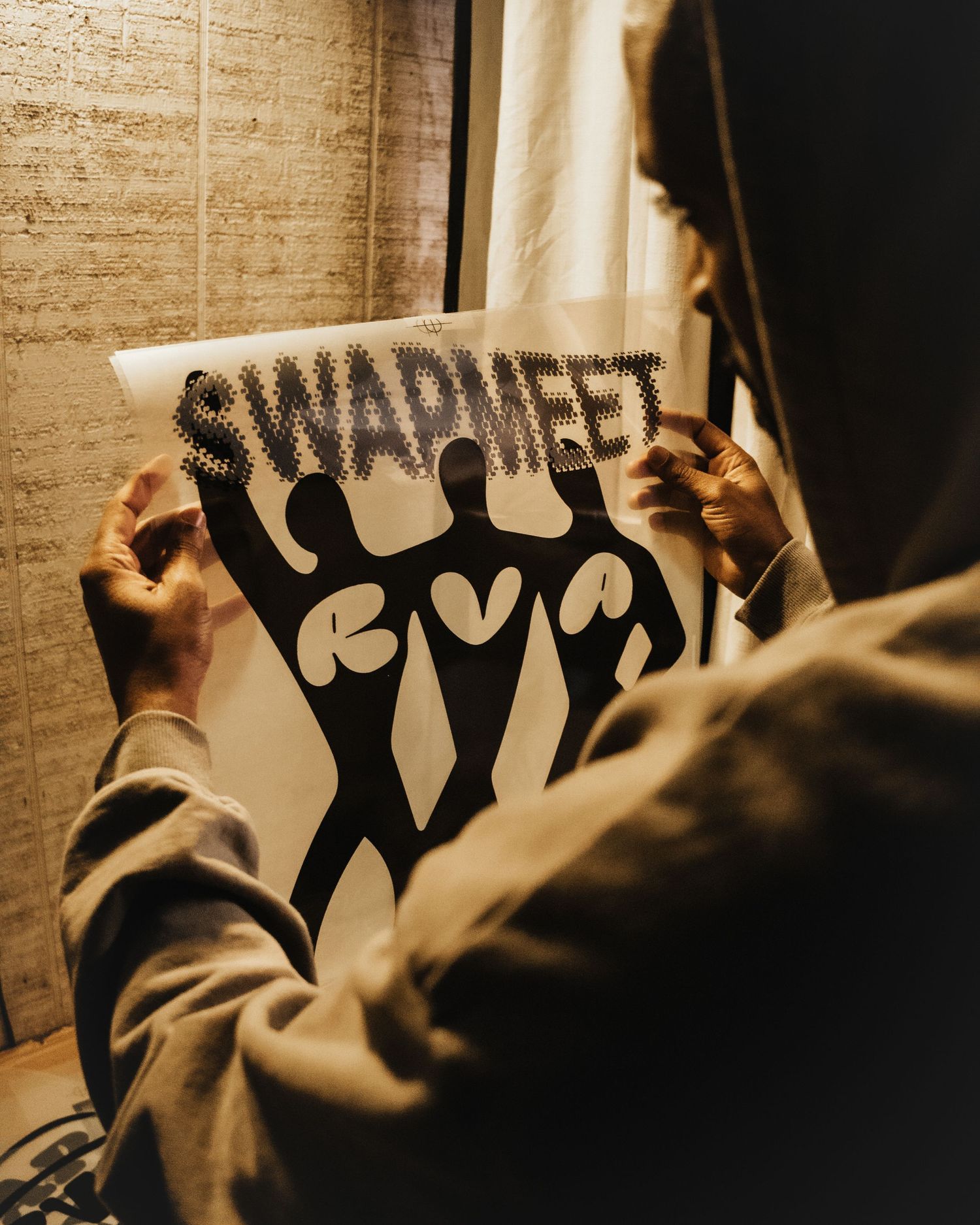 Silhouettes of people holding up protest signs against a textured brick wall background.