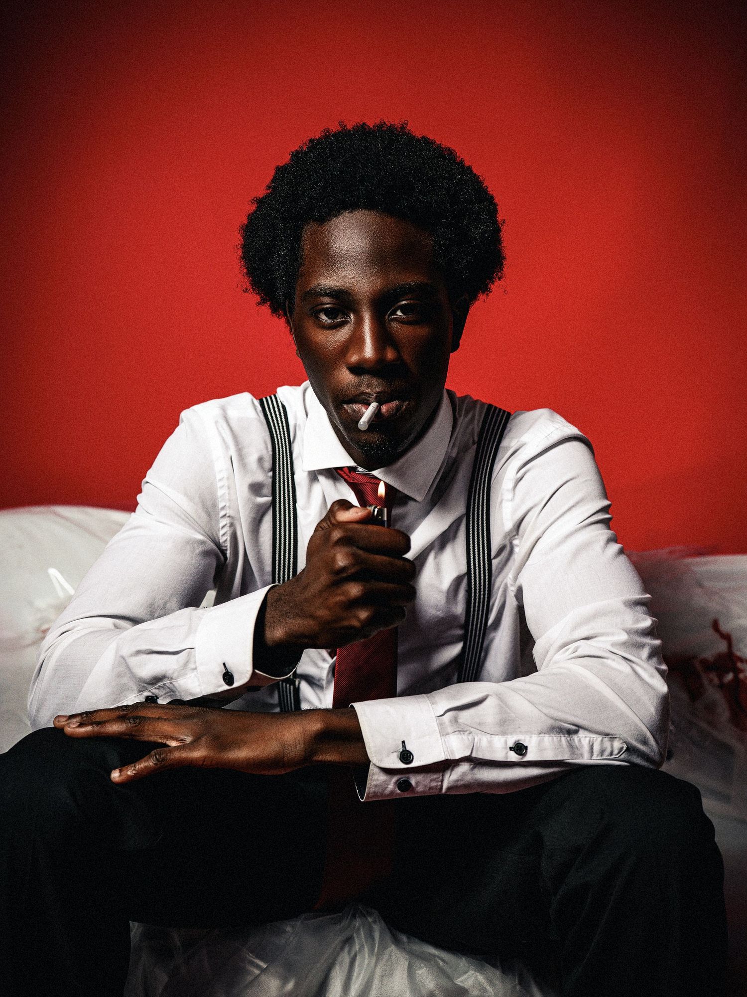 Portrait series against a red background featuring white dress shirt and suspenders styling.