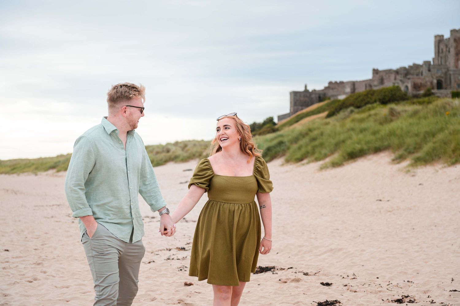 Engaged couple walking along Northumberland beach for pre-wedding photos, North East England
