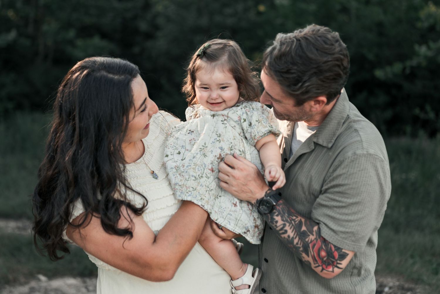 Family smiling together during an outdoor summer session with a Kansas City family photographer