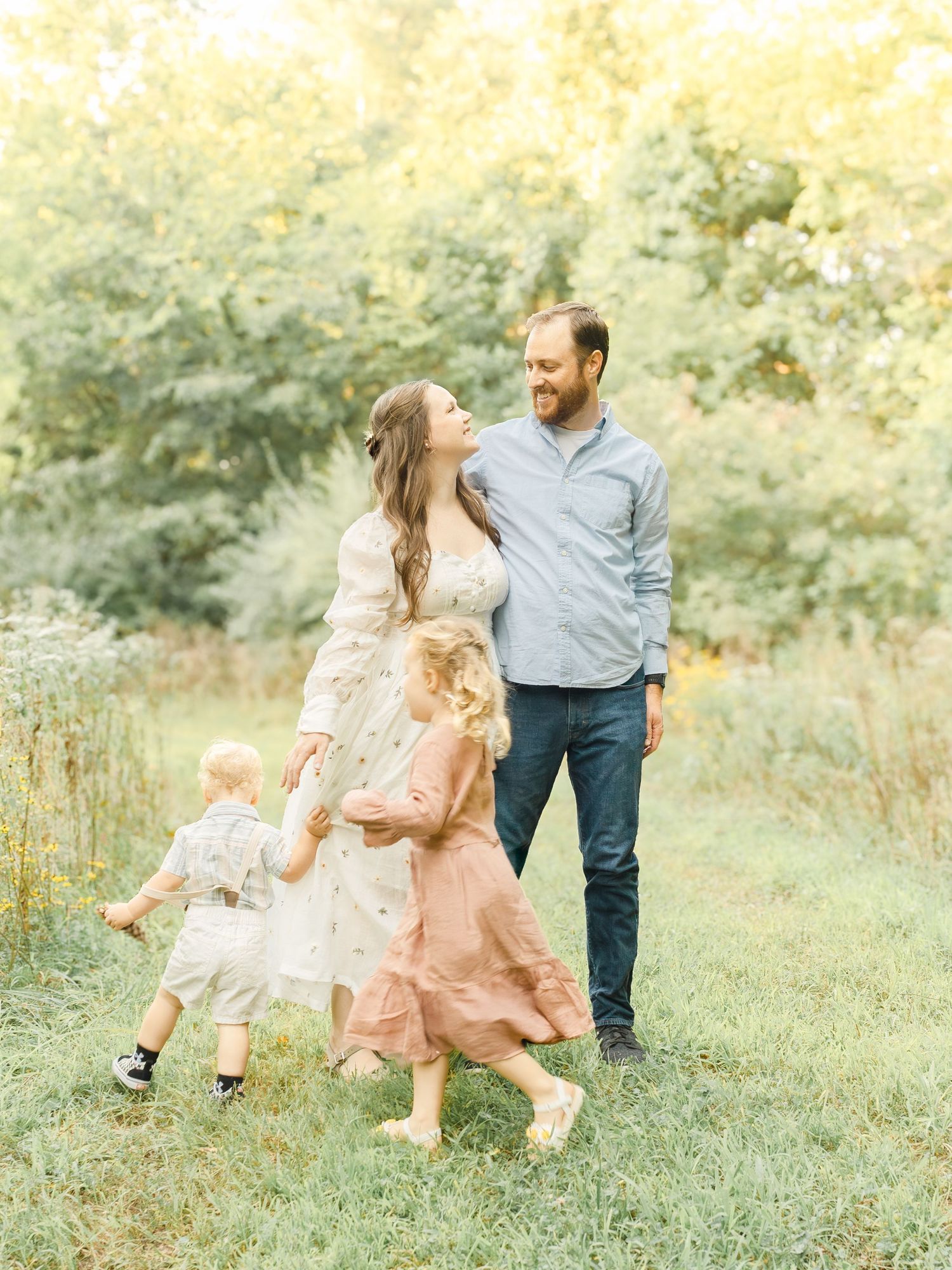 Parents walking with their two children during a relaxed outdoor family session in Kansas City at golden hour.