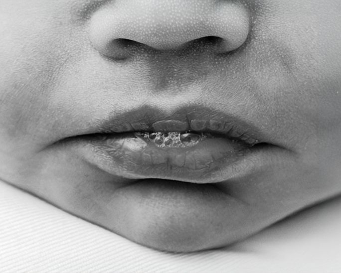 Close-up black and white photo of a baby's lips and nose, showing delicate infant facial features.