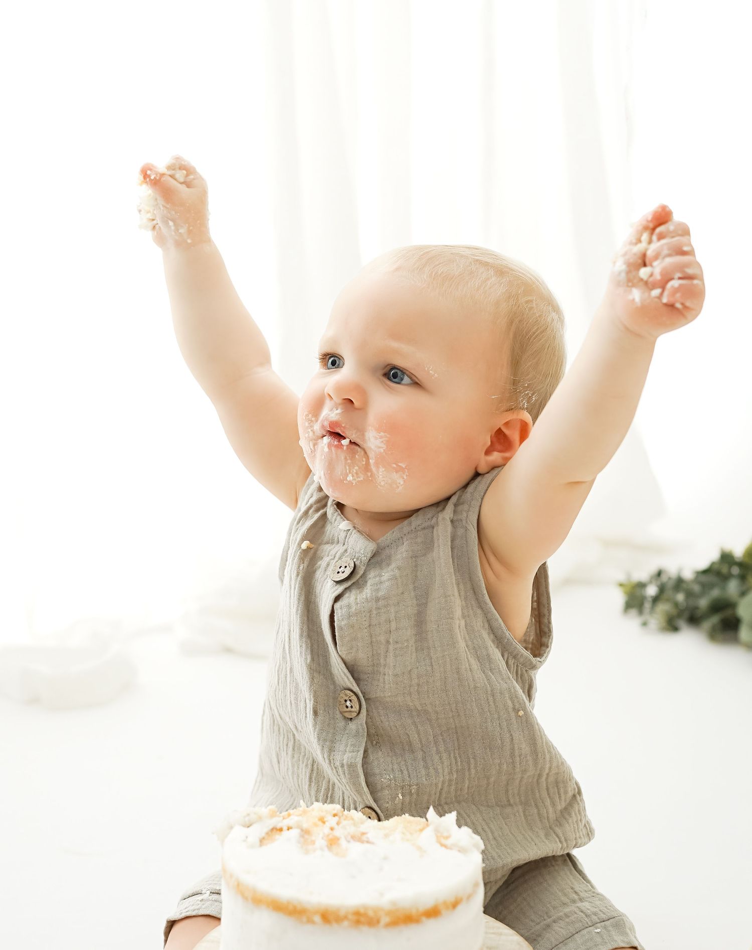 Baby celebrating first birthday with cake during simple milestone session in studio