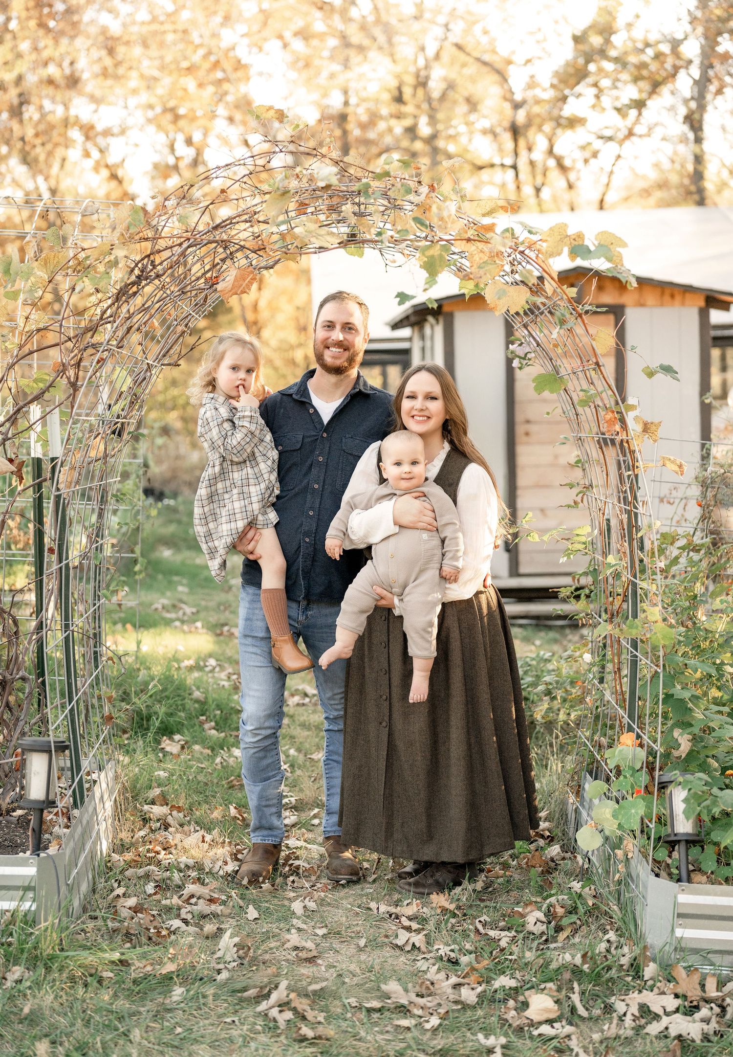 Family of four posing together in front of their home during an outdoor family photography session.