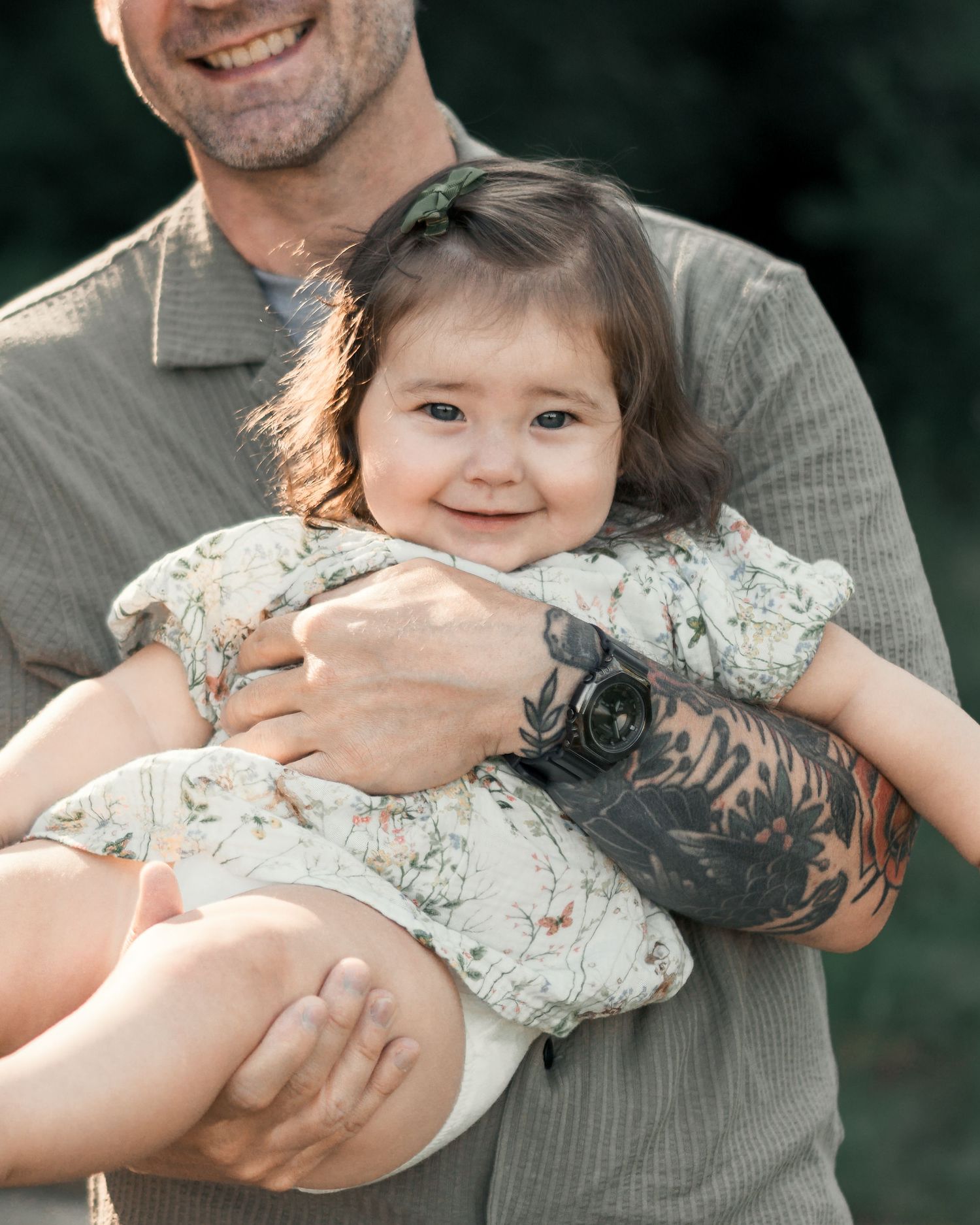 Smiling toddler sitting in her father's arms during a relaxed family photo session.