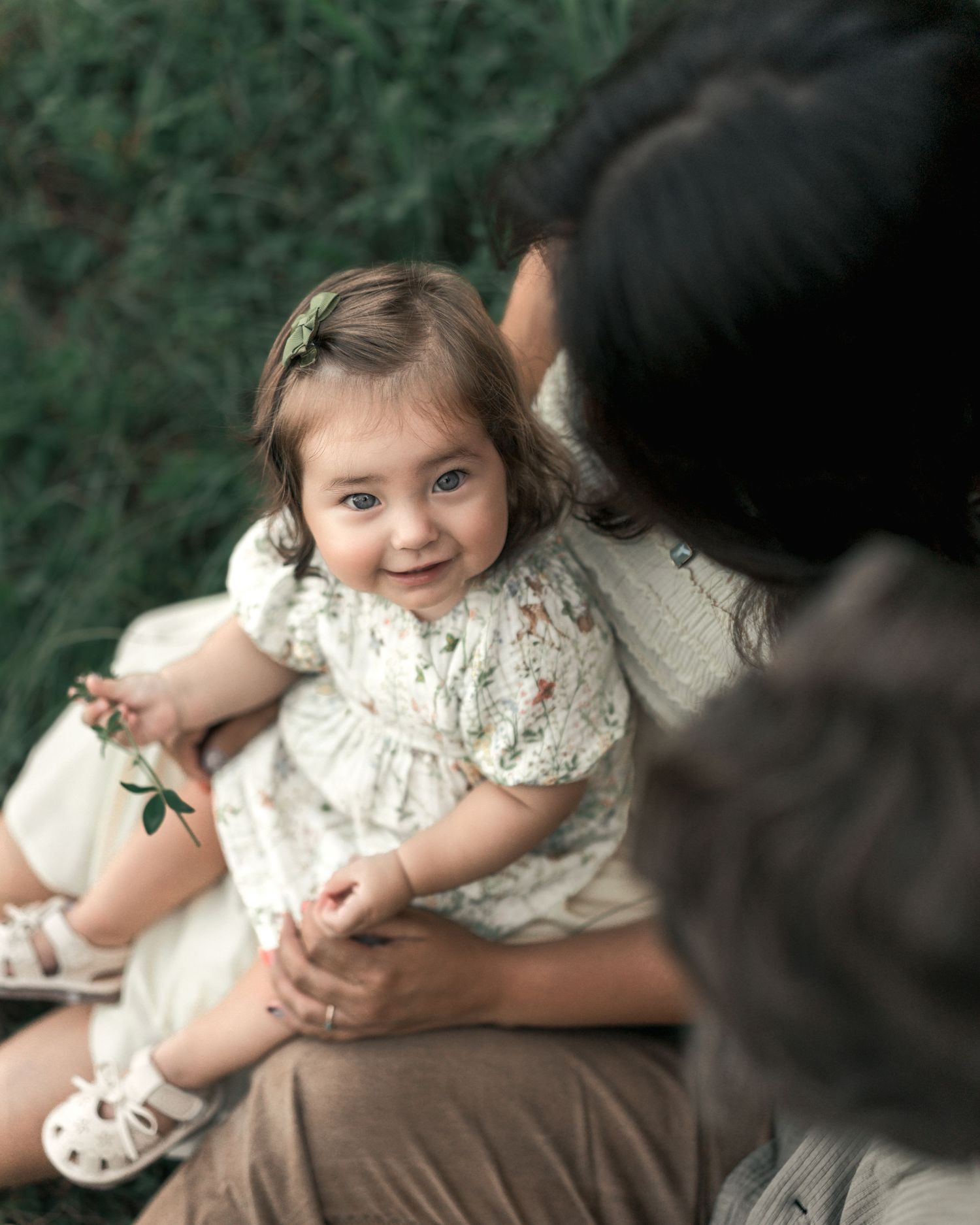 Curious toddler smiling while sitting with her parents during a relaxed family portrait.
