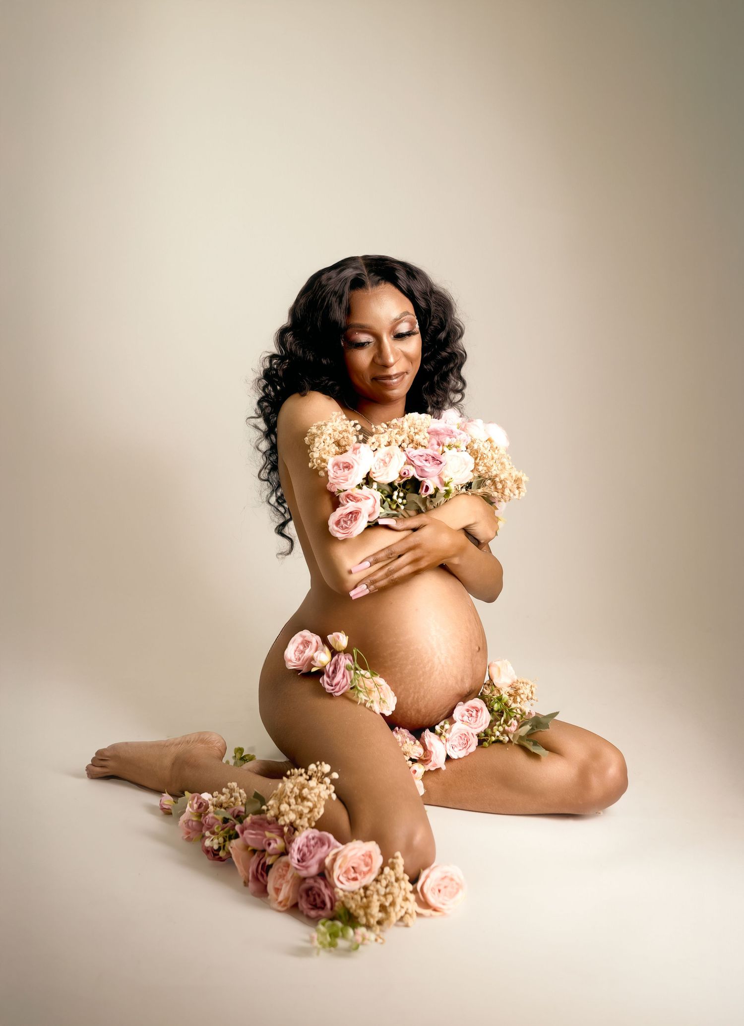 Artistic maternity portrait with floral accents and soft neutral tones, photographed in a Kansas City studio maternity session