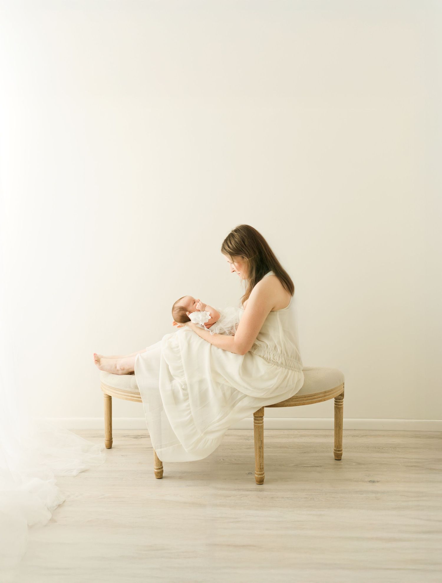 Mother holding baby on bench during soft motherhood session in Kansas City studio