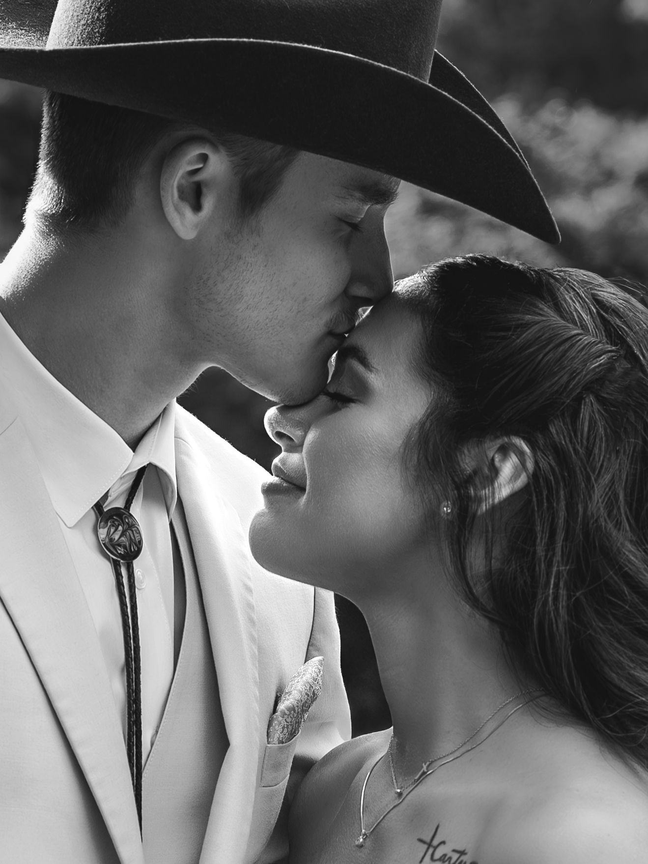 black and white photo of groom kissing bride's forehead