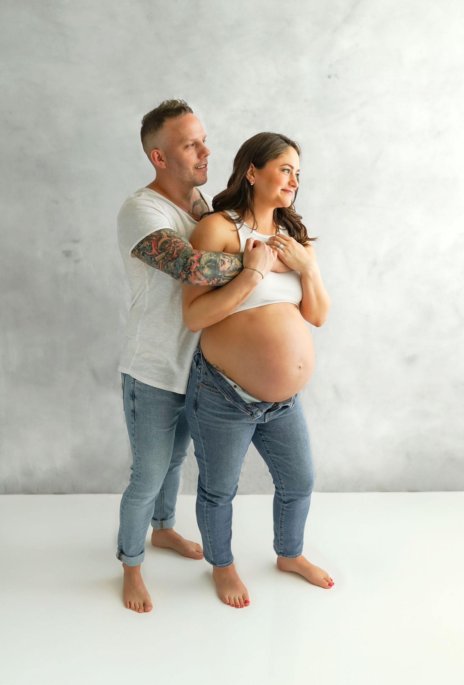 Expectant parents with their toddler during a studio maternity photography session.