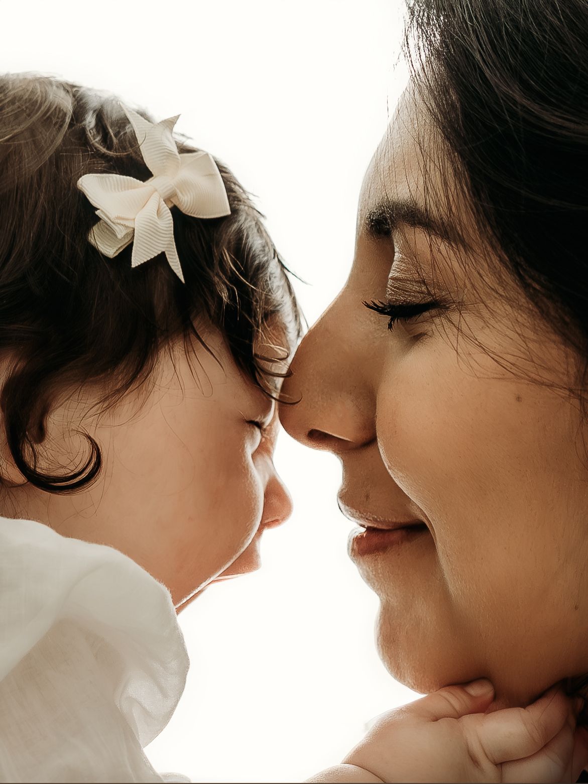 Mother touching noses with her young daughter during a heartfelt motherhood photography session.