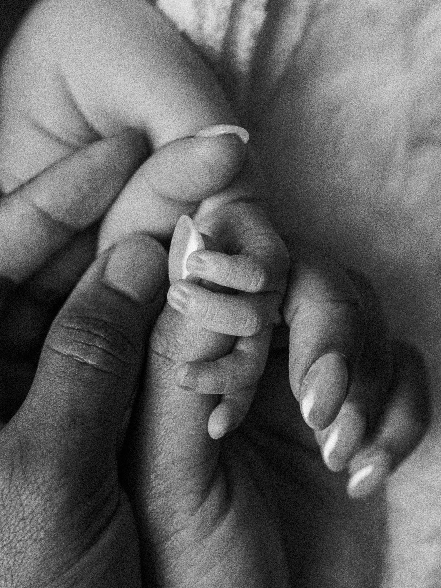 Close-up black and white portrait of a newborn baby holding a parent's finger during a Kansas City newborn photography session.