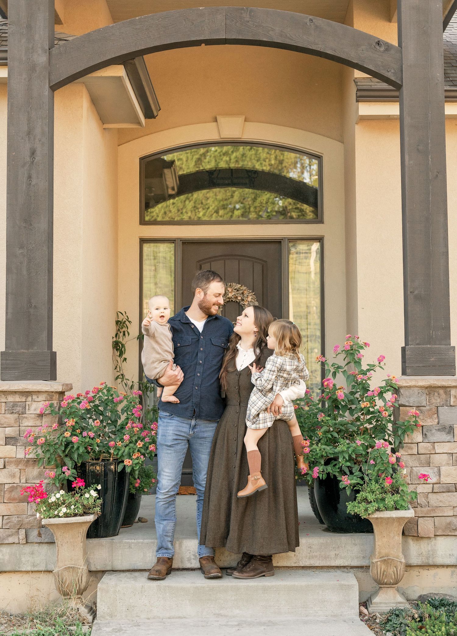 Family of four standing together on their front porch during a Front Porch Portrait session.
