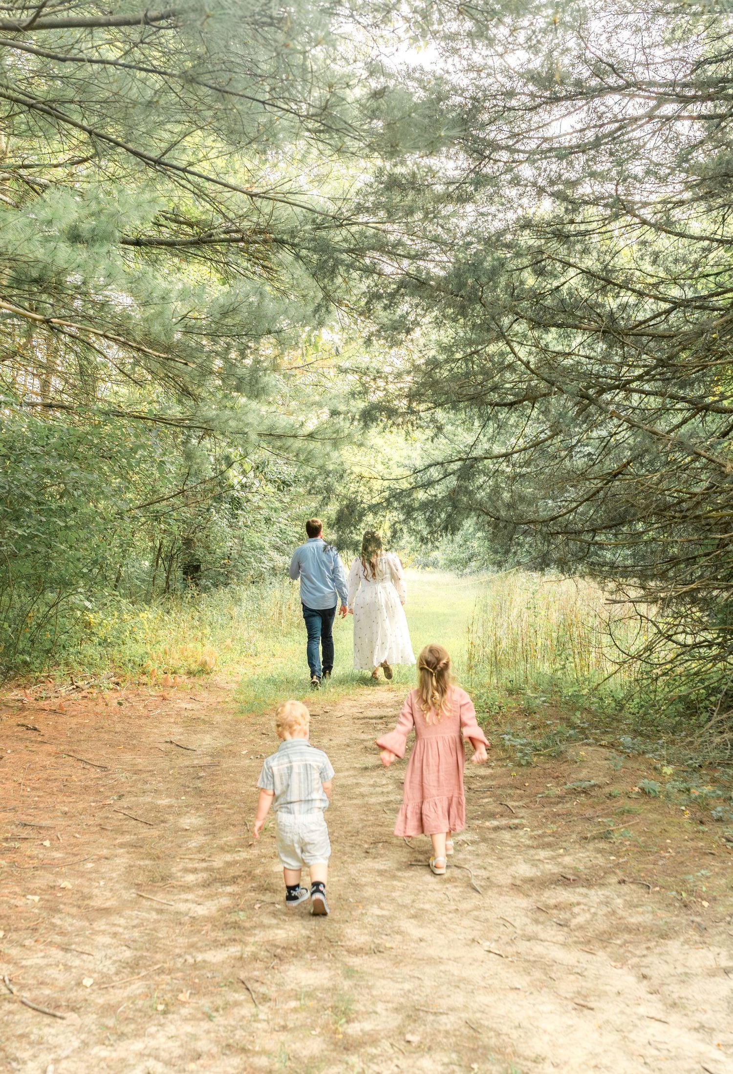 A family walking down a wooded path during an outdoor family photo session in Kansas City.