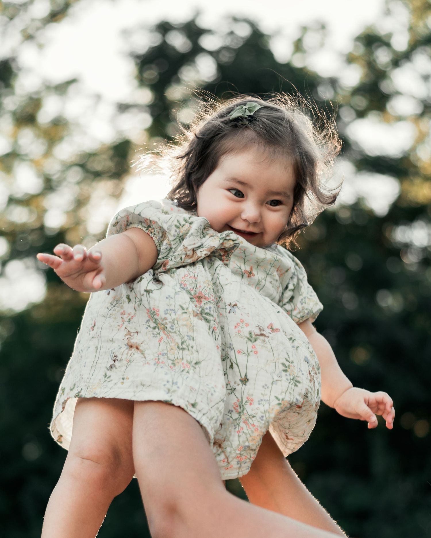 Toddler reaching toward the camera during a playful outdoor photo session.
