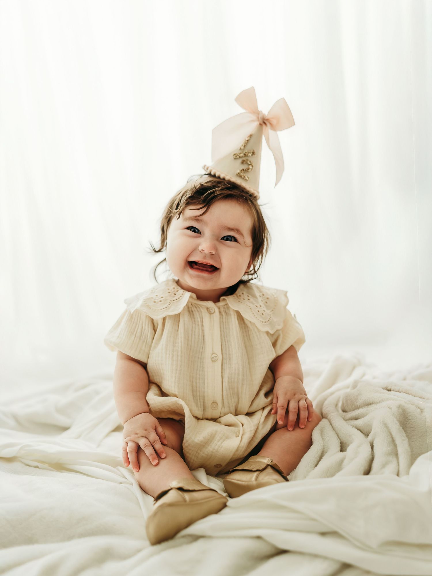 6 month old baby girl sitting and smiling in a neutral studio milestone session.