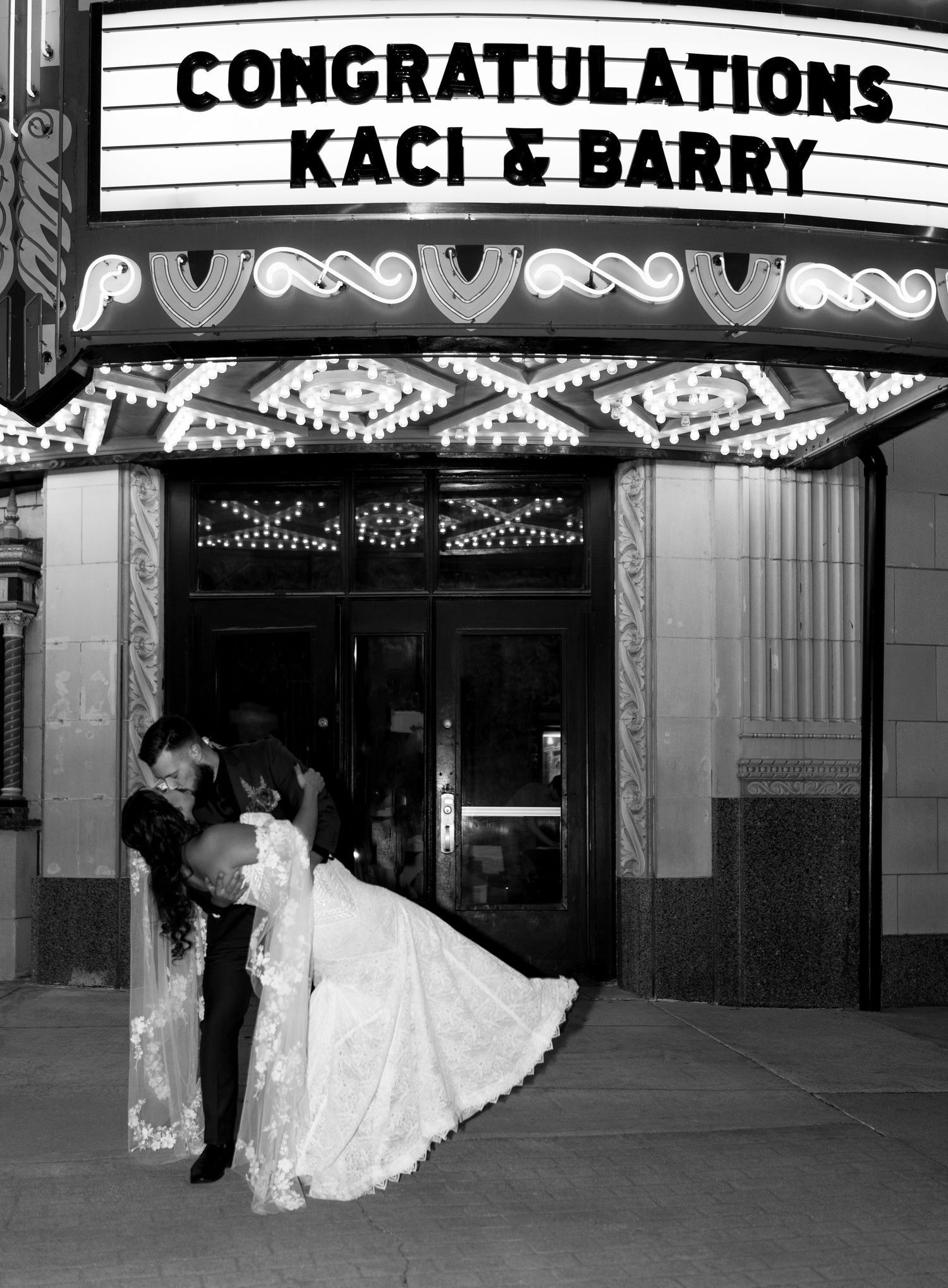 A silhouetted couple shares a romantic dip kiss under an illuminated theater marquee reading 'Congratulations Kaci & Barry'.