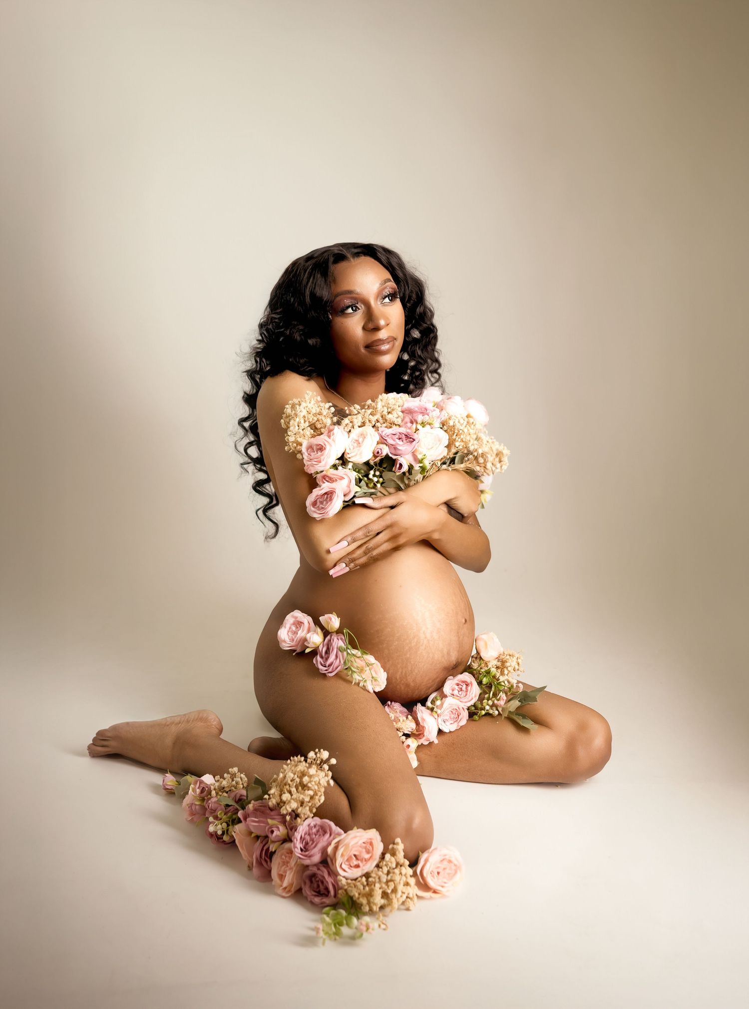 Artistic maternity portrait with floral accents and soft neutral tones, photographed in a Kansas City studio maternity session