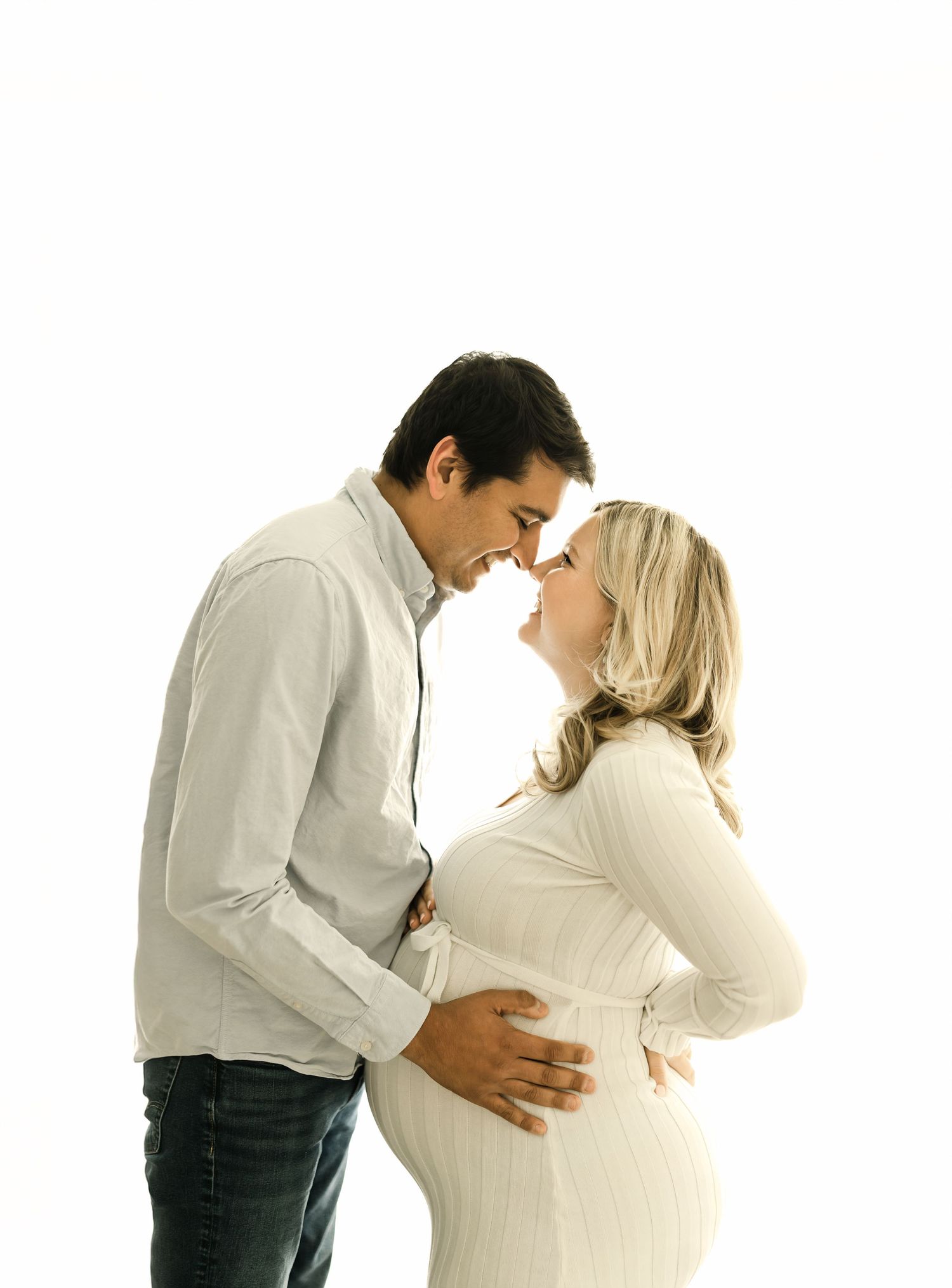 A series of pregnancy progression photos showing a couple embracing as the woman's belly grows larger over time.
