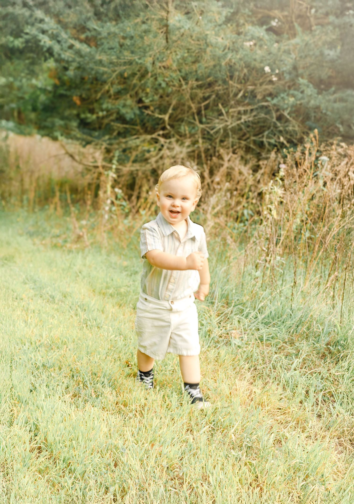 A young boy walking through a grassy field during a natural outdoor family session.