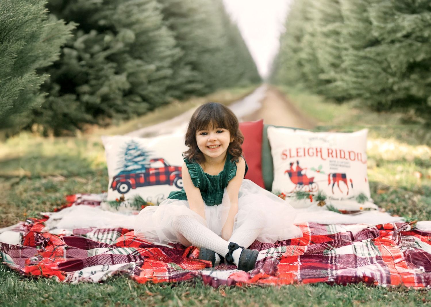 A young girl in chistrmas dress on a festive blanket at a tree farm in Kansas City