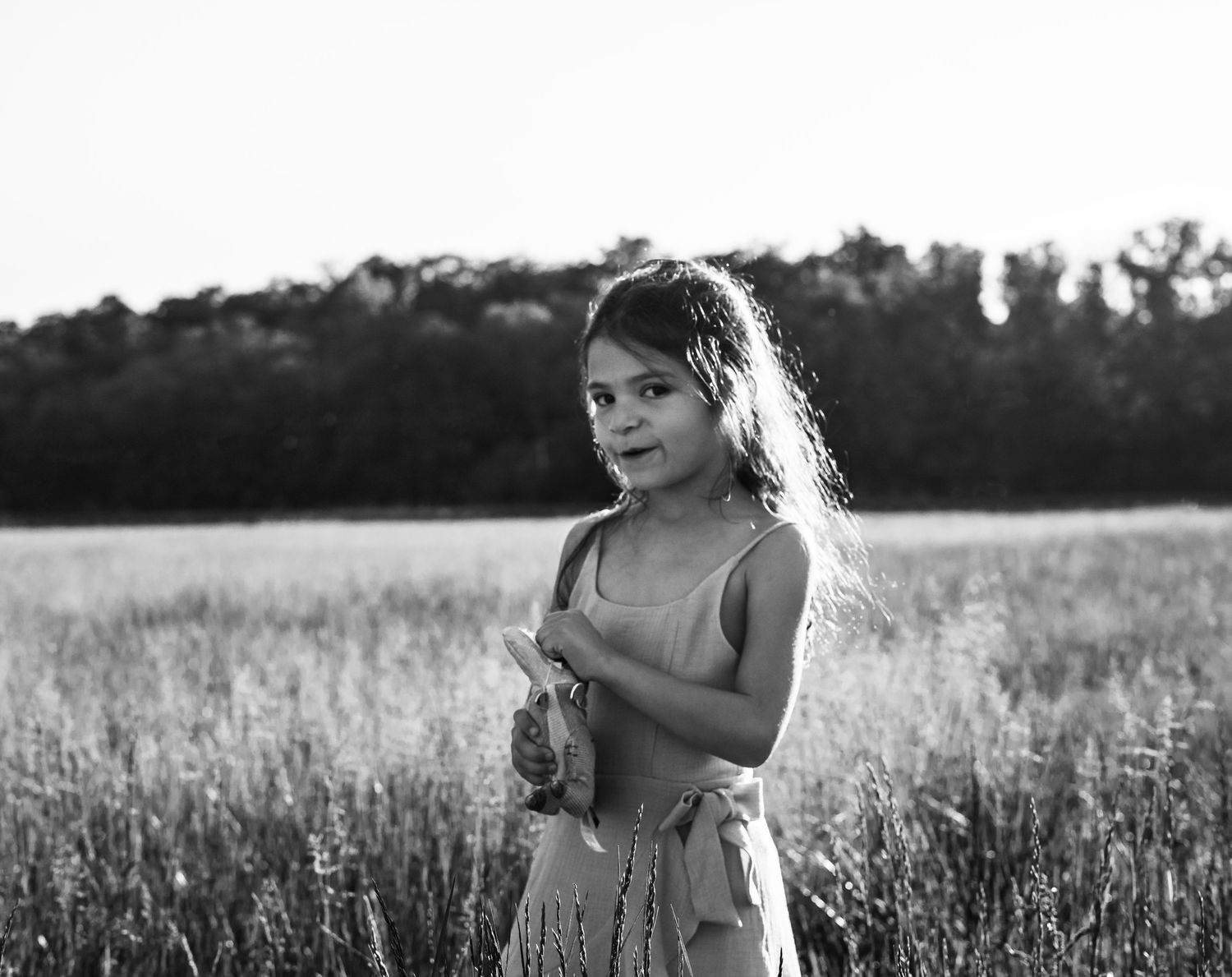 Young girl standing in field during outdoor child portrait session in Kansas City