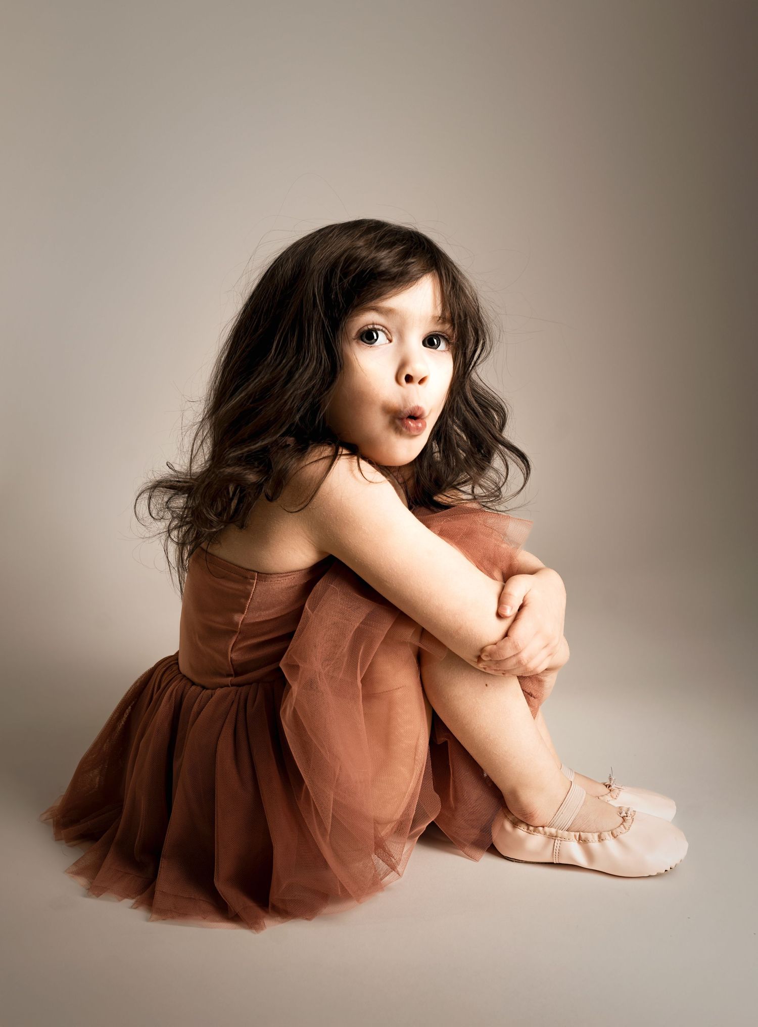 Young girl sitting in studio wearing dress during milestone portrait session Kansas City