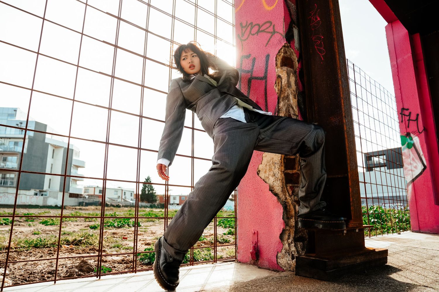 Man in grey suit jumping dynamically near colorful graffiti wall in urban setting.