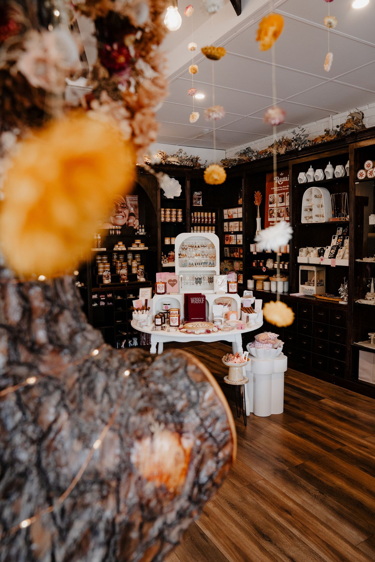 Interior of Remi and Mars boutique store with dark shelving, dried floral decor, and product displays.