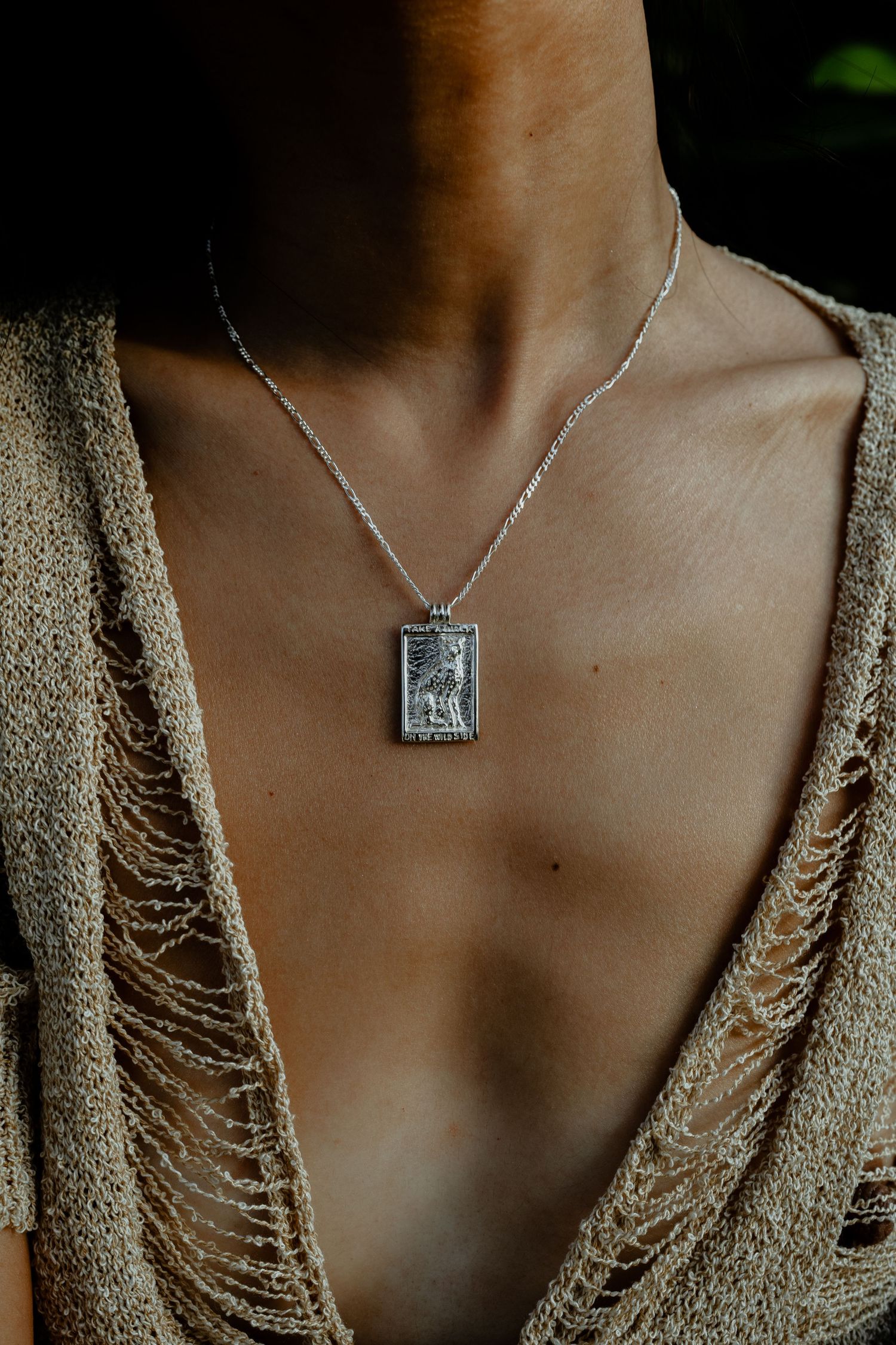 Silver rectangular tarot card pendant necklace on a chain worn over a distressed knit top.