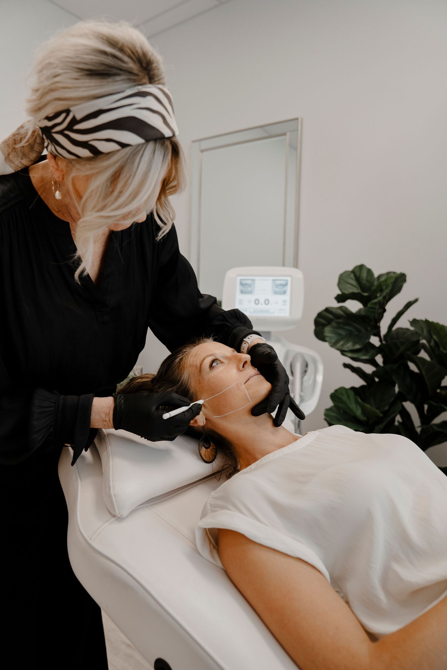 Esthetician in black gloves performing a facial treatment on a client in a beauty clinic.