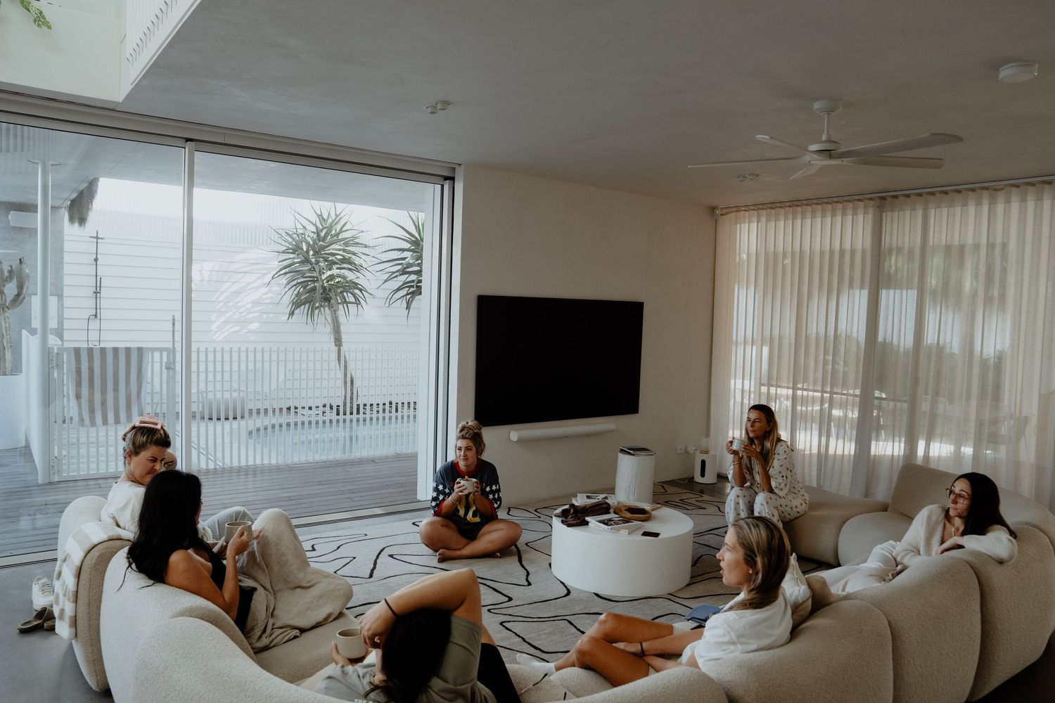 Group of women relaxing on white sofas in a modern bright living room.