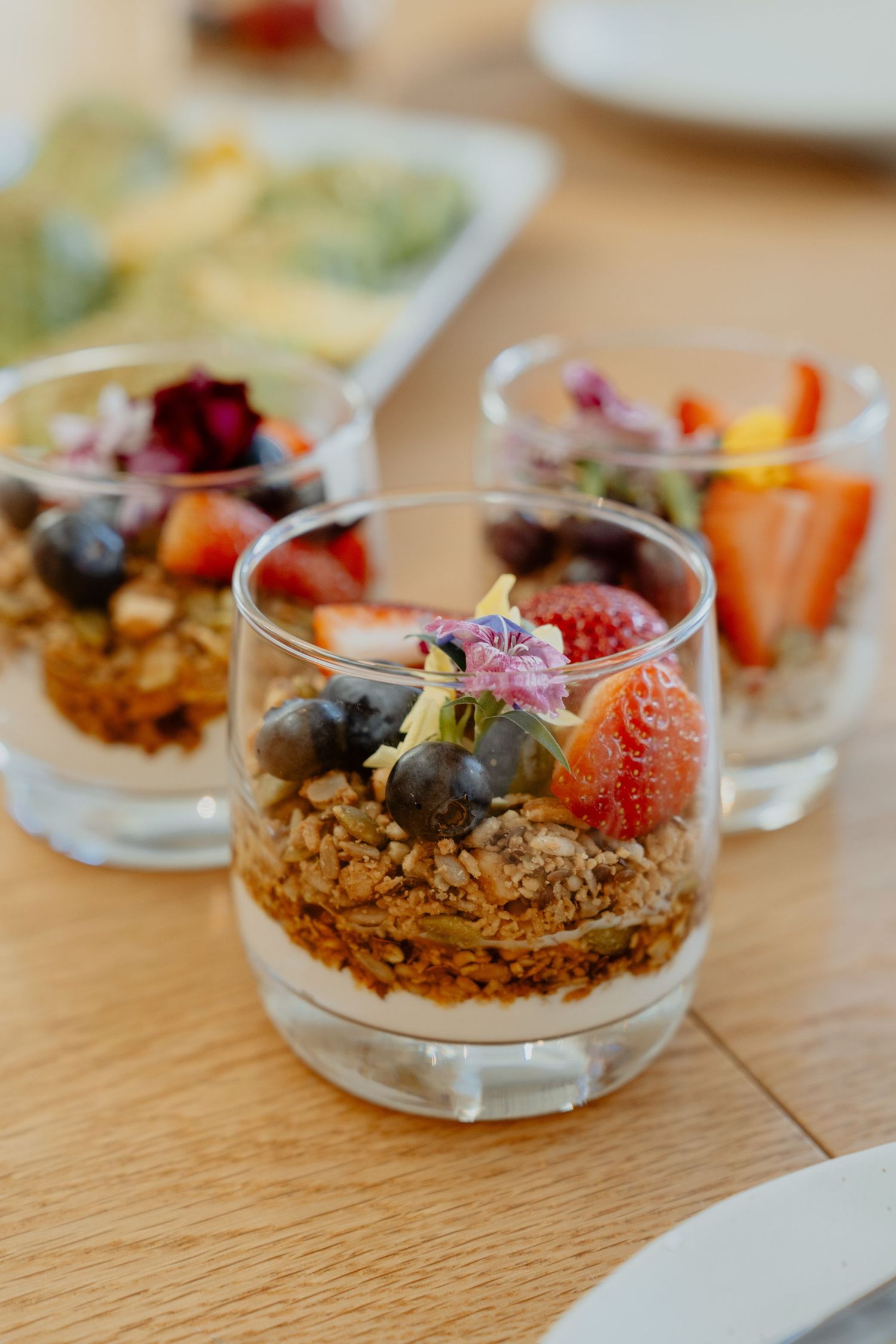 Elegant granola parfait glasses topped with fresh berries and edible flowers.