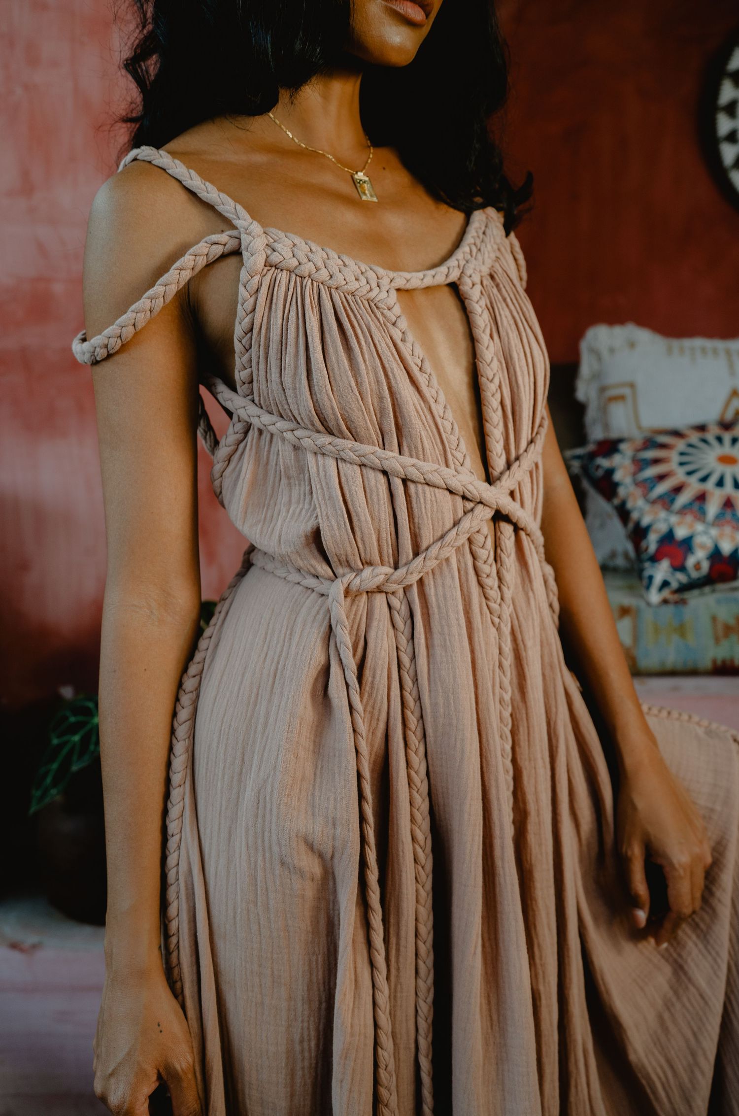 Close-up of woman in beige pleated macrame dress with gold necklace.