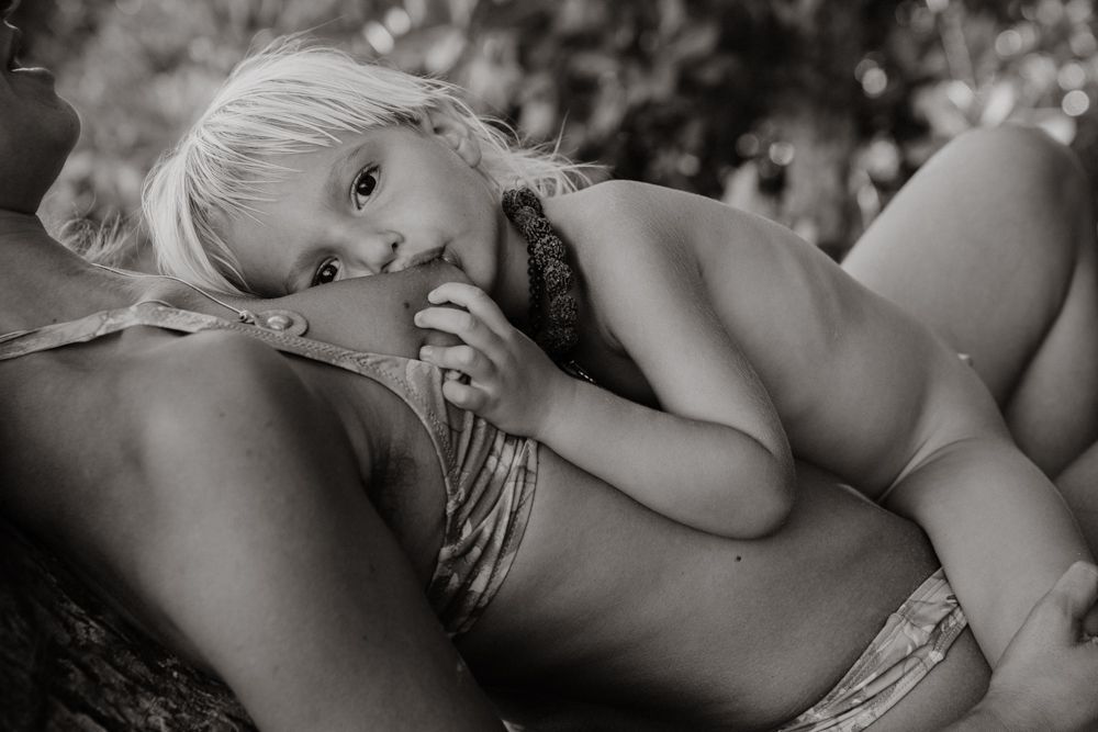 Young child resting on adult lap in black and white outdoor portrait.
