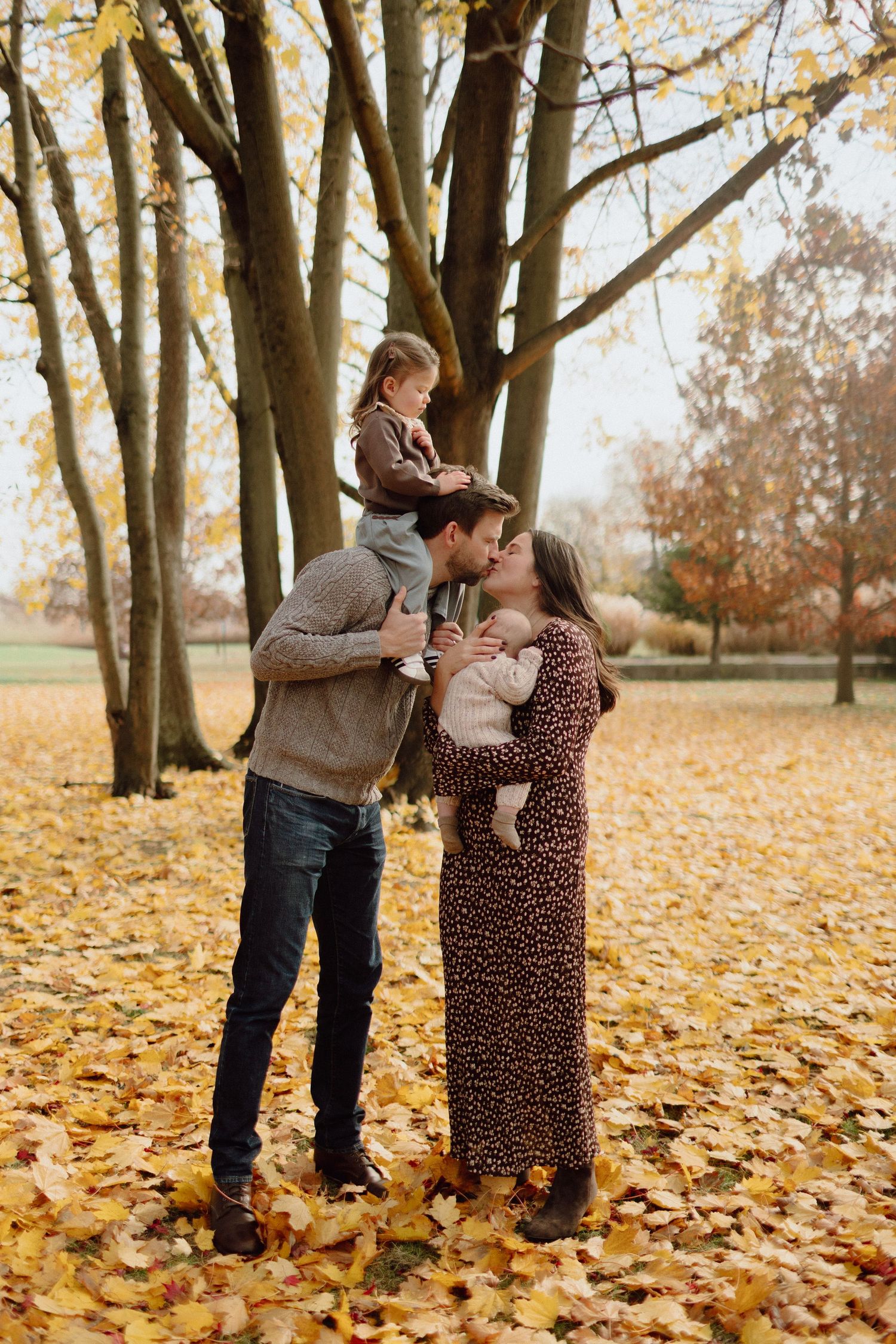 A family shares tender moments among fallen autumn leaves in a park in Fairfield, CT.