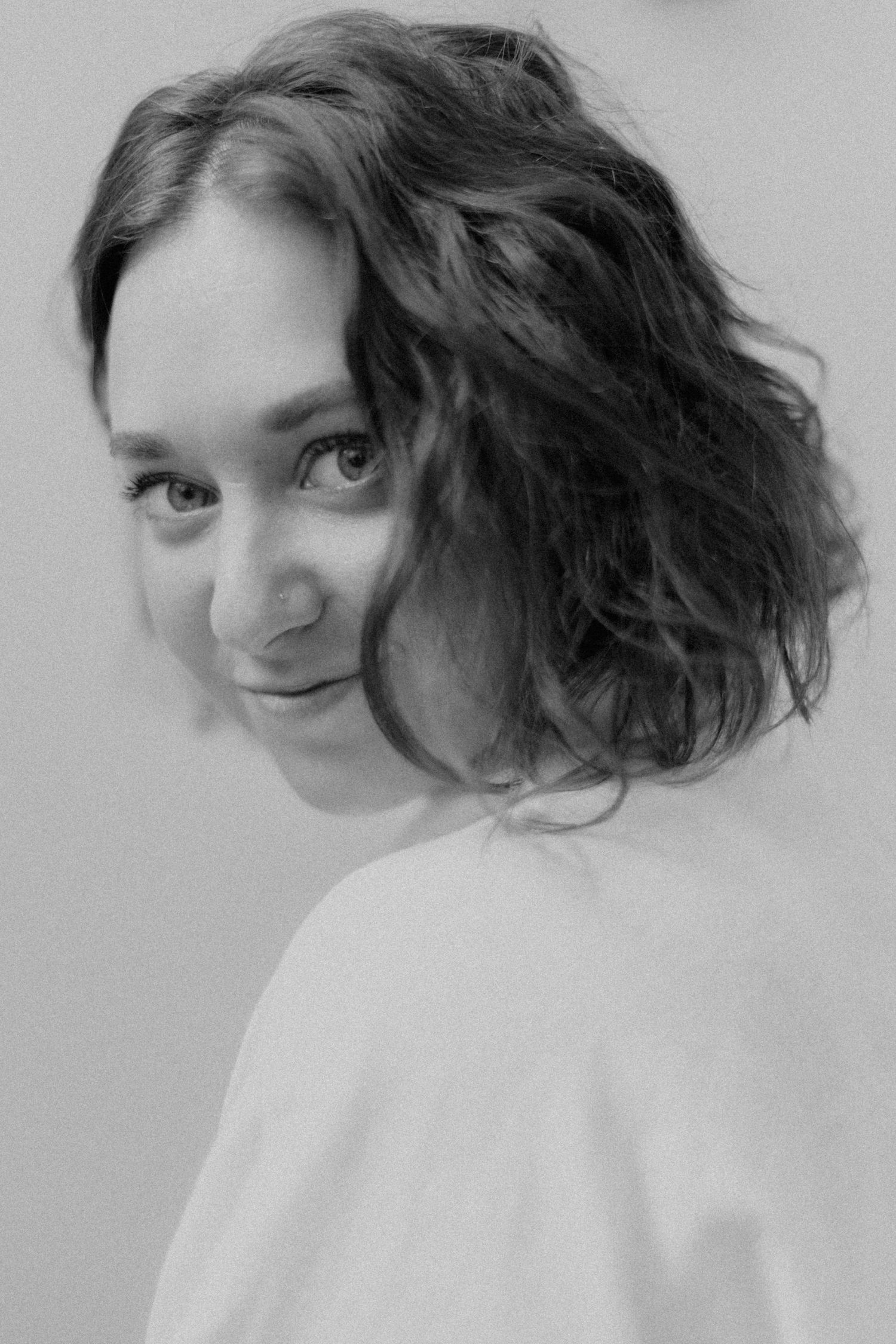 Artistic black and white portrait series showing playful over-the-shoulder poses.