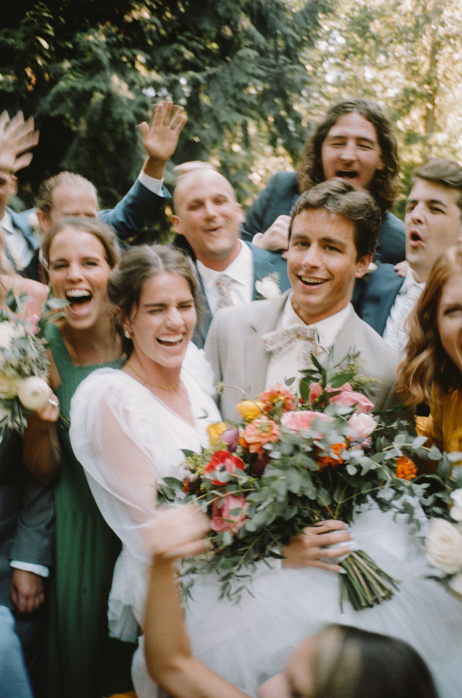 Joyful wedding party celebration with bride holding colorful bouquet surrounded by guests in Los Angeles, CA.