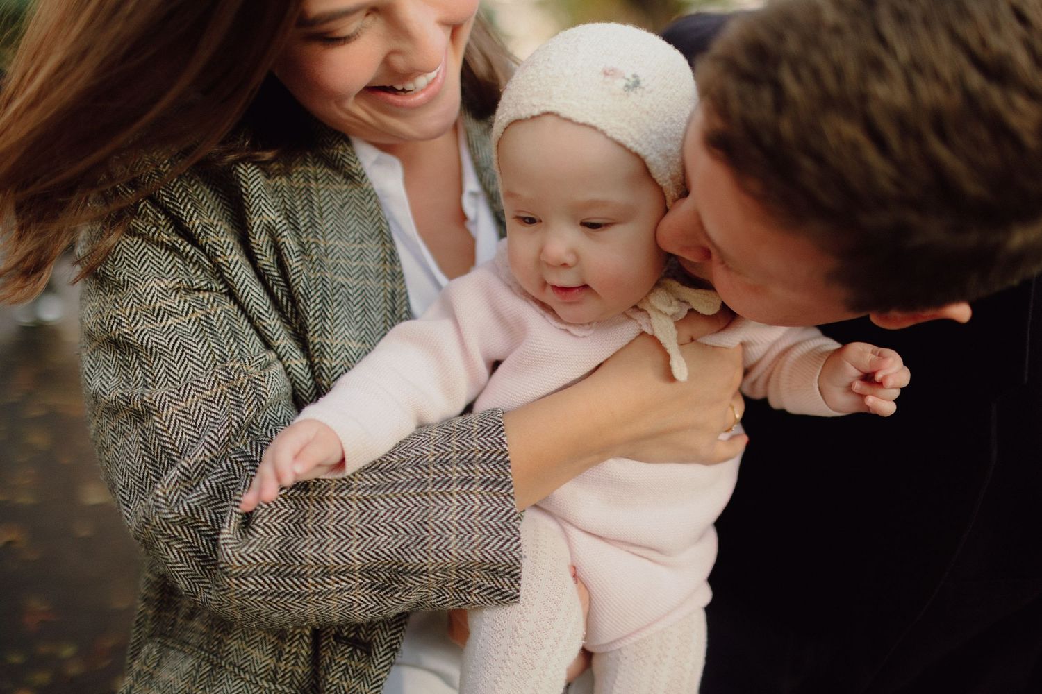 A tender moment between parent and baby wearing pink in warm natural lighting during a family photo session.