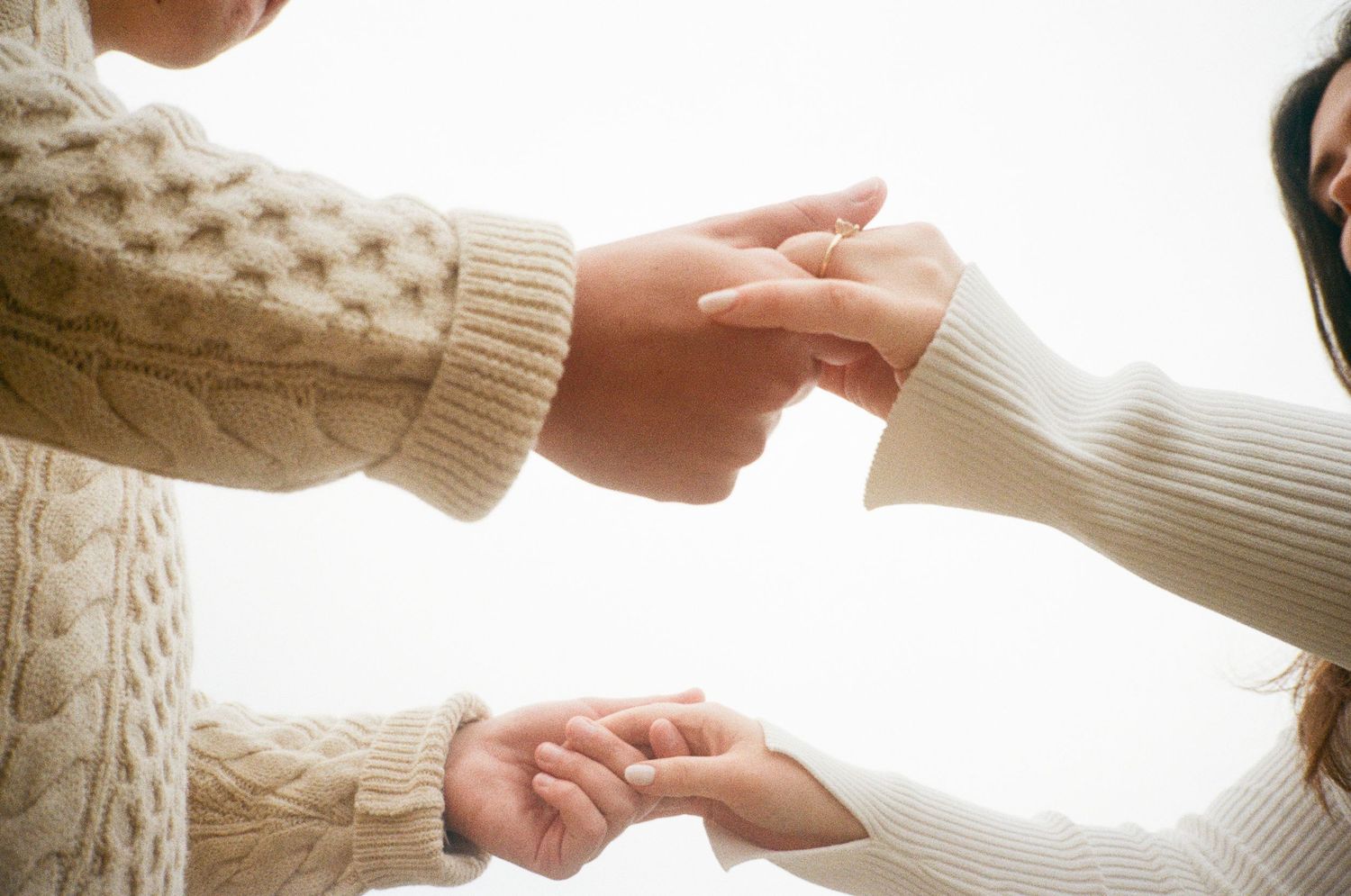 Close-up of hands holding each other wearing cozy cable knit sweaters.