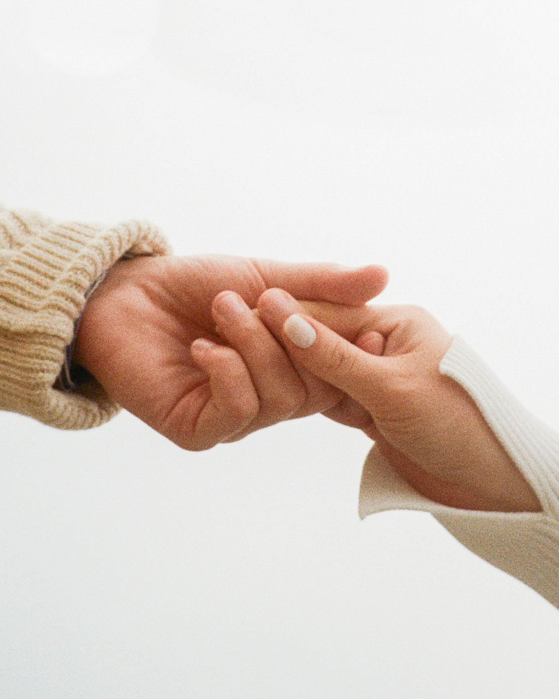 Two hands reaching out and gently touching each other in a supportive gesture against a white background.