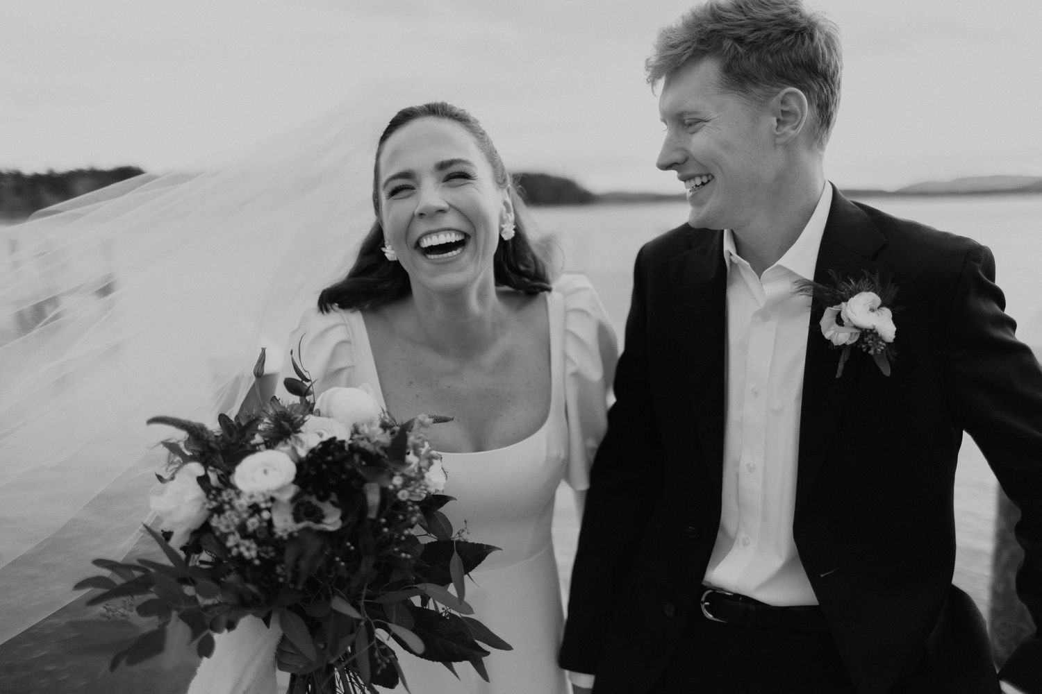 A joyful couple shares candid laughs and embraces during their outdoor wedding photo session.