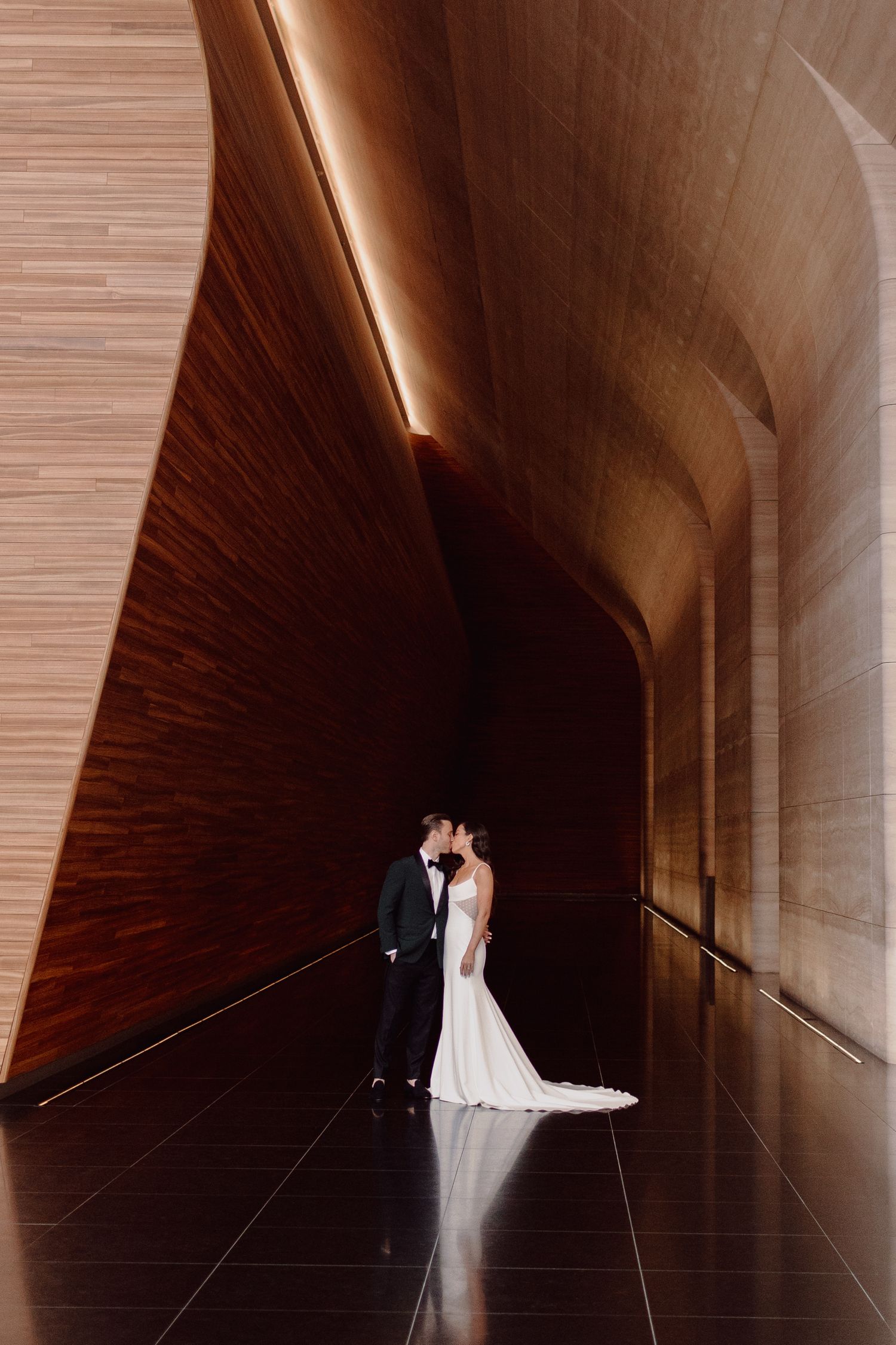 A dramatic architectural corridor with a couple in wedding attire creating artistic shadows in New York City.