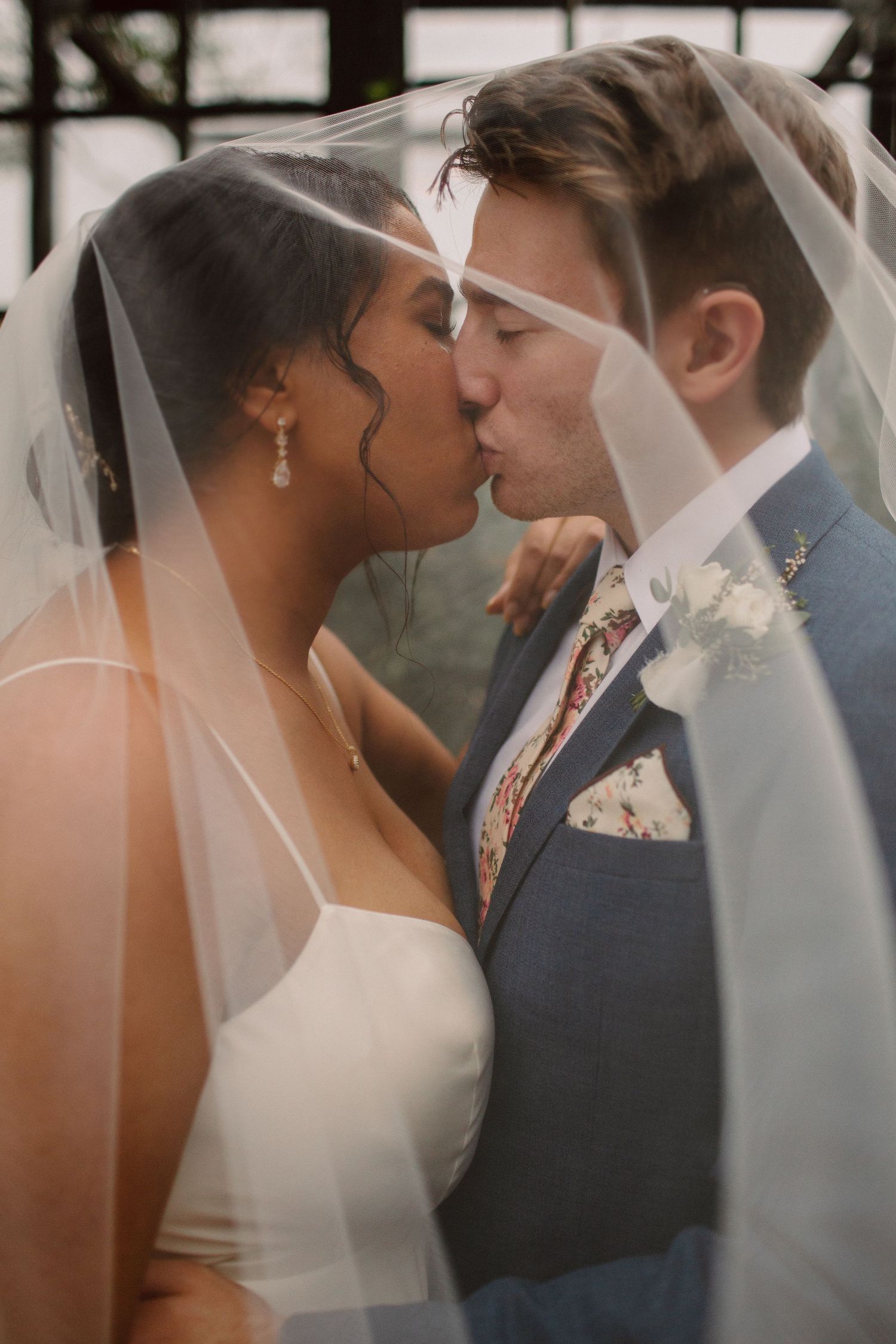 A romantic wedding couple shares an intimate moment under a delicate white veil during their ceremony.