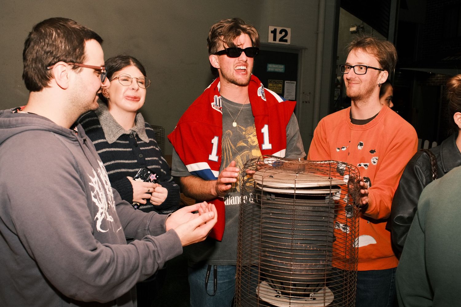 Group of young adults gathered around an industrial machine exhibit at a museum or science center.