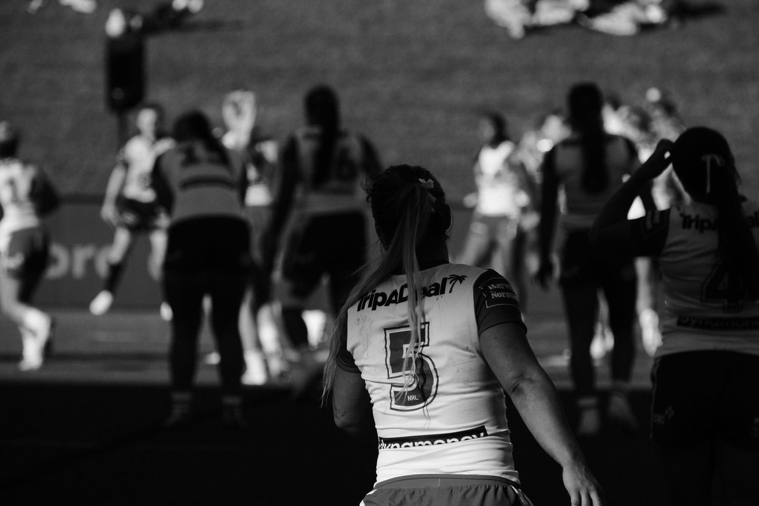 Black and white photo of female rugby player wearing number 5 jersey on field during a match.