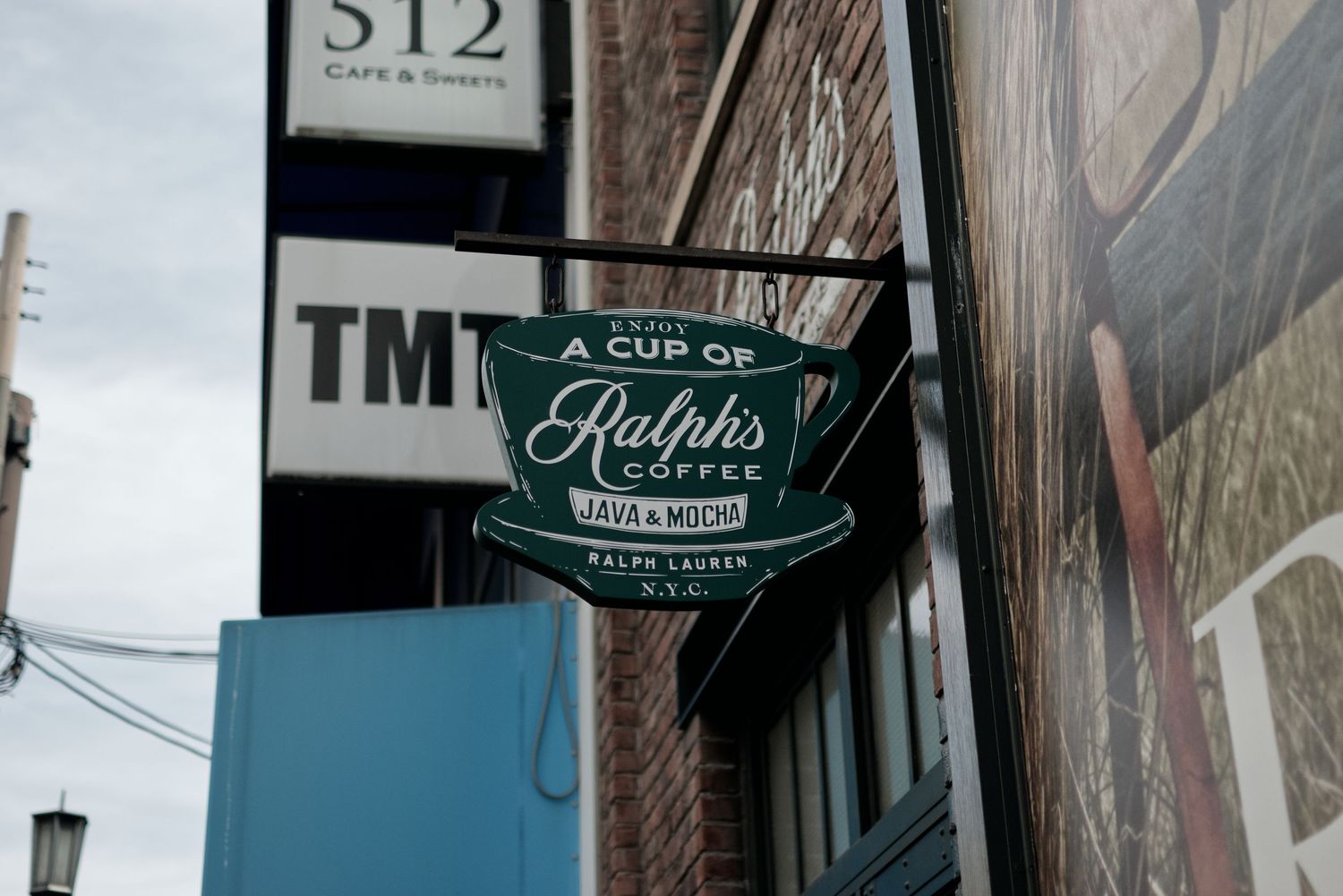 Ralph's Coffee shop sign hanging on a brick building exterior in New York City.