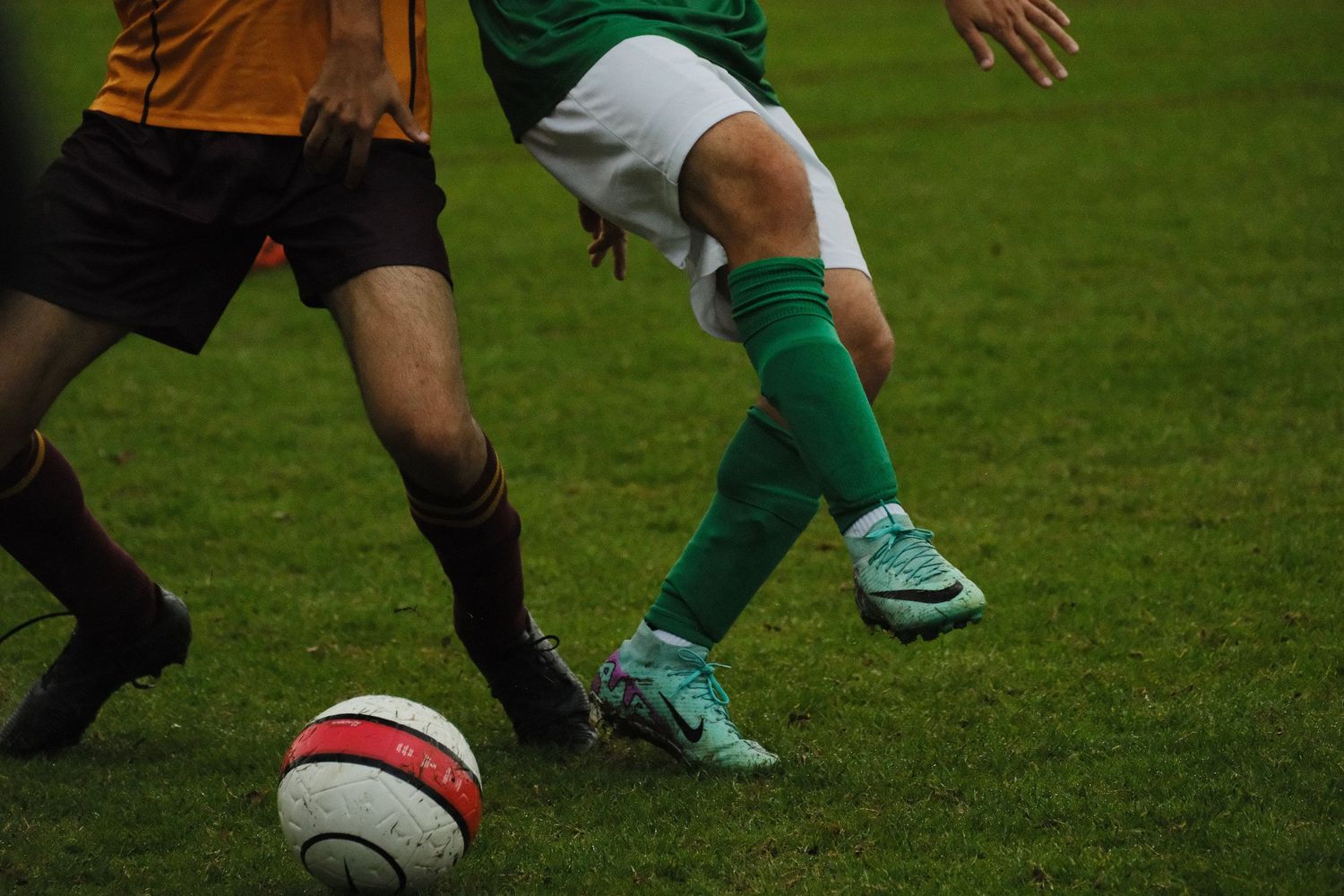 Two soccer players competing for the ball on a green grass field during a match.