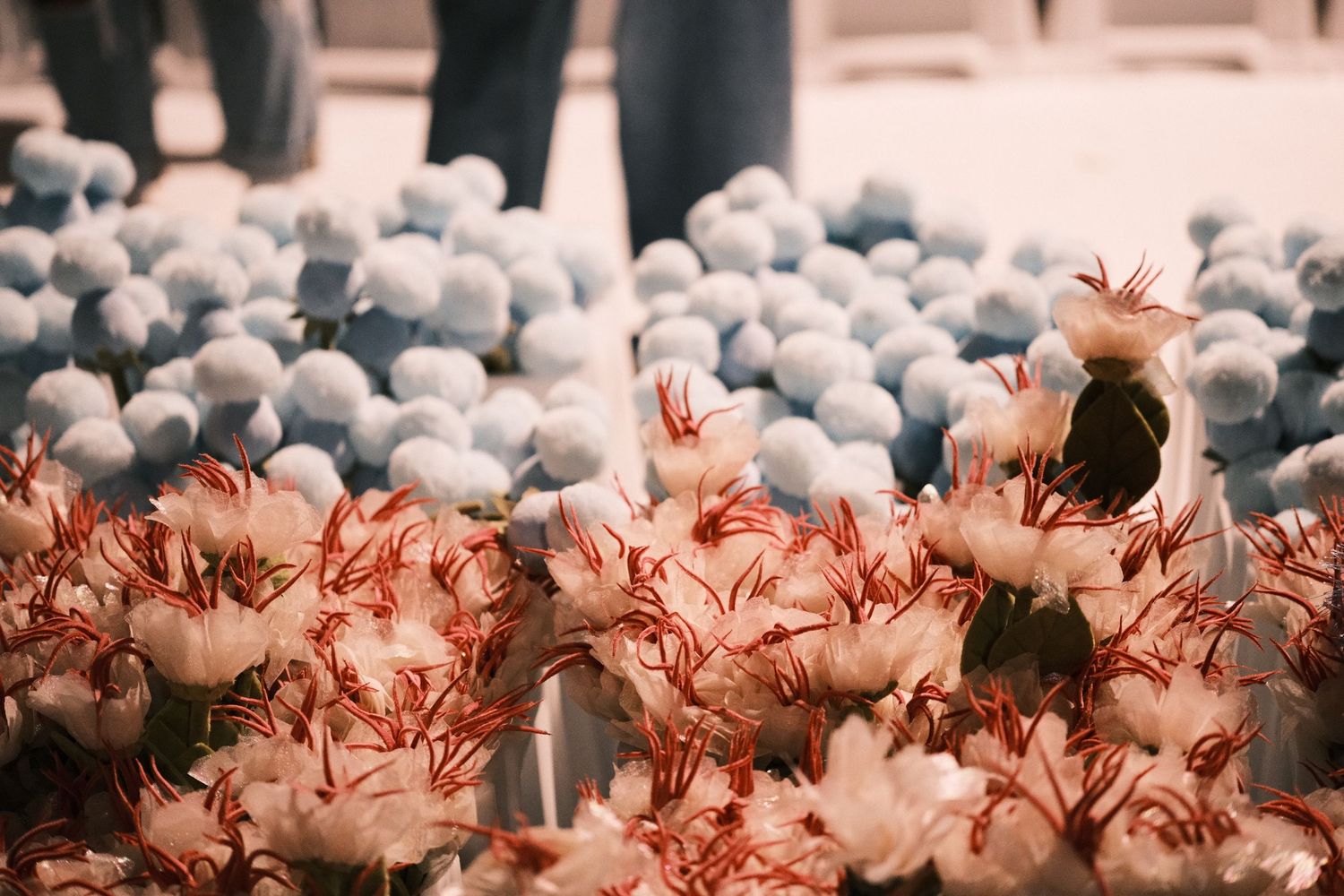 Close-up of elegant white and red flowers with soft blue spheres on a decorative floor.
