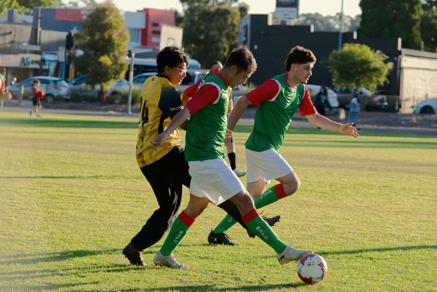Young soccer players competing for the ball during a youth football match on a green field.